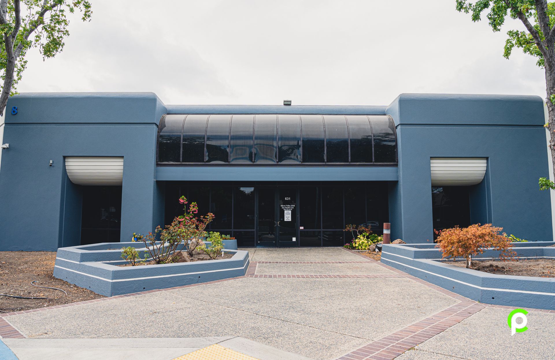 A large blue building with a driveway in front of it