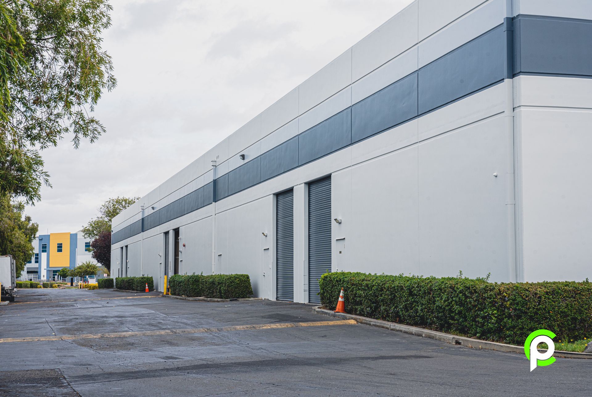 A large white building with a lot of doors and bushes in front of it.