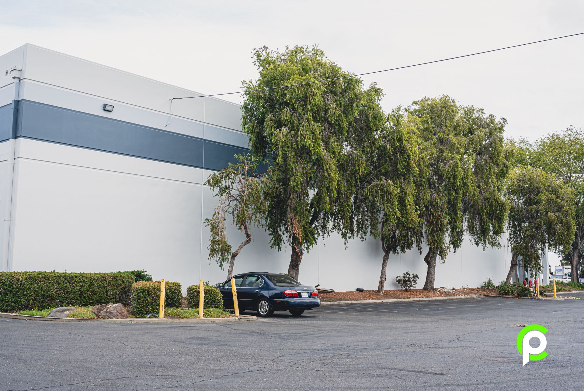 A black car is parked in front of a large white building