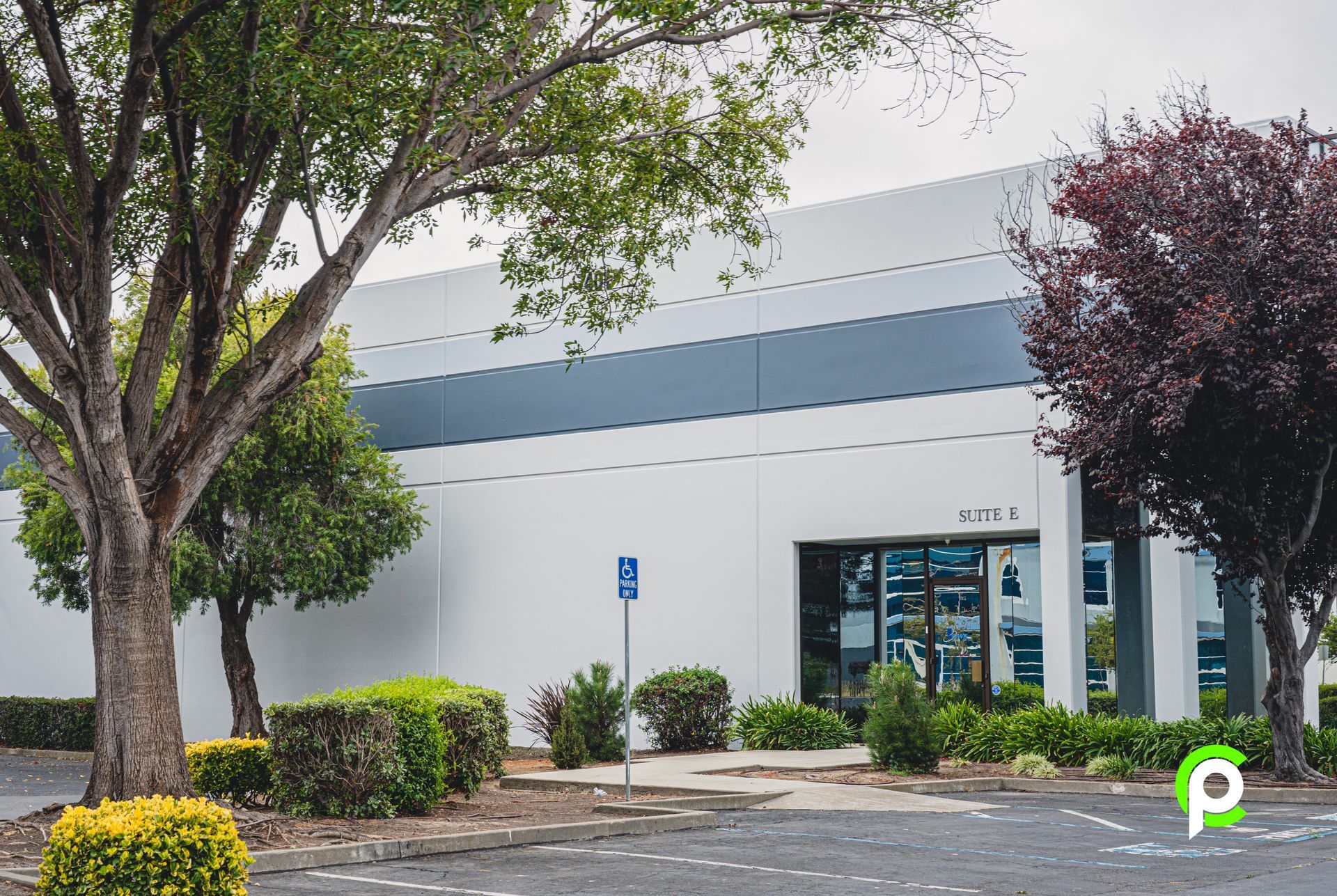 A white building with a handicapped parking sign in front of it