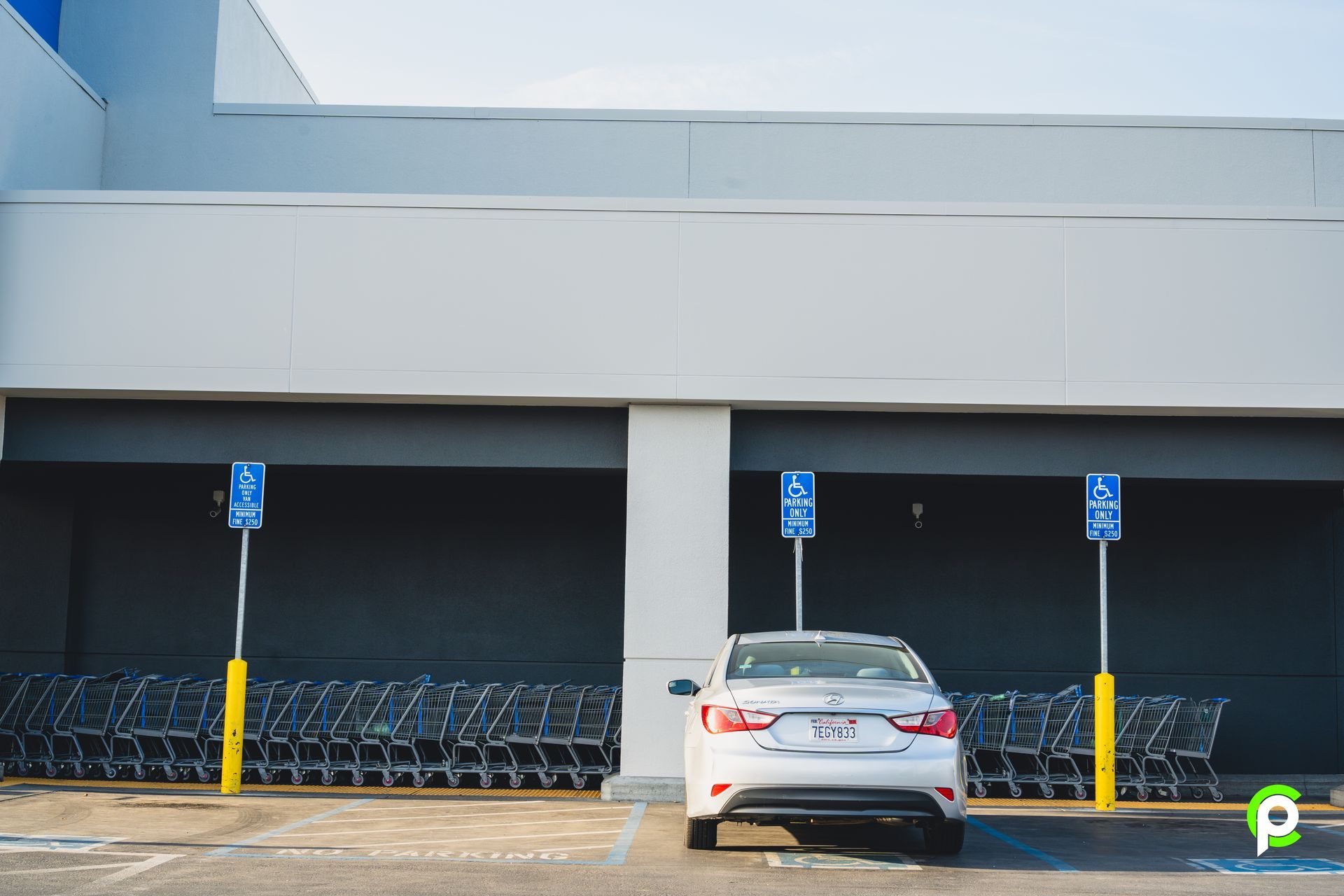 A white car is parked in a parking lot next to a row of shopping carts.