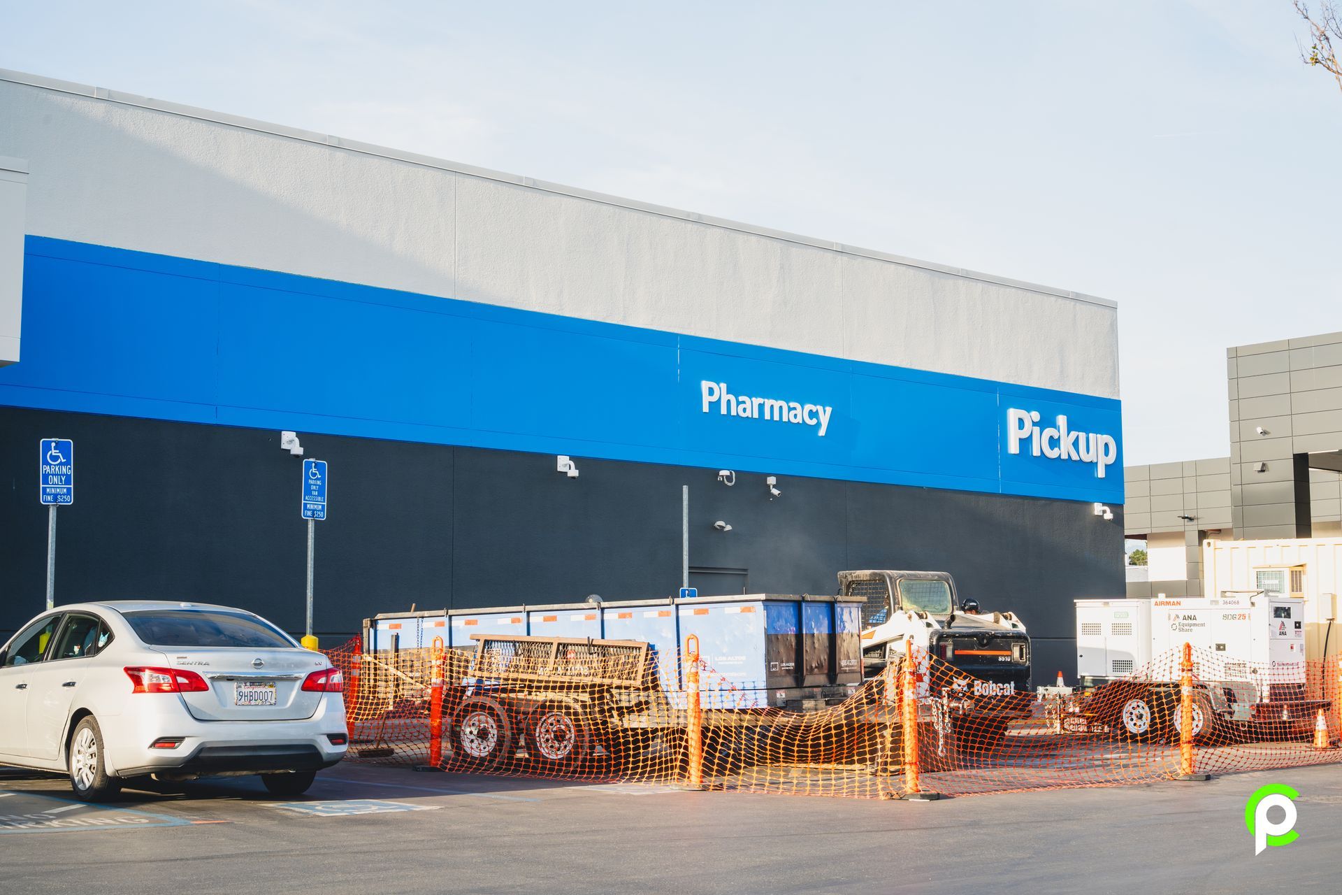 A white car is parked in front of a pharmacy