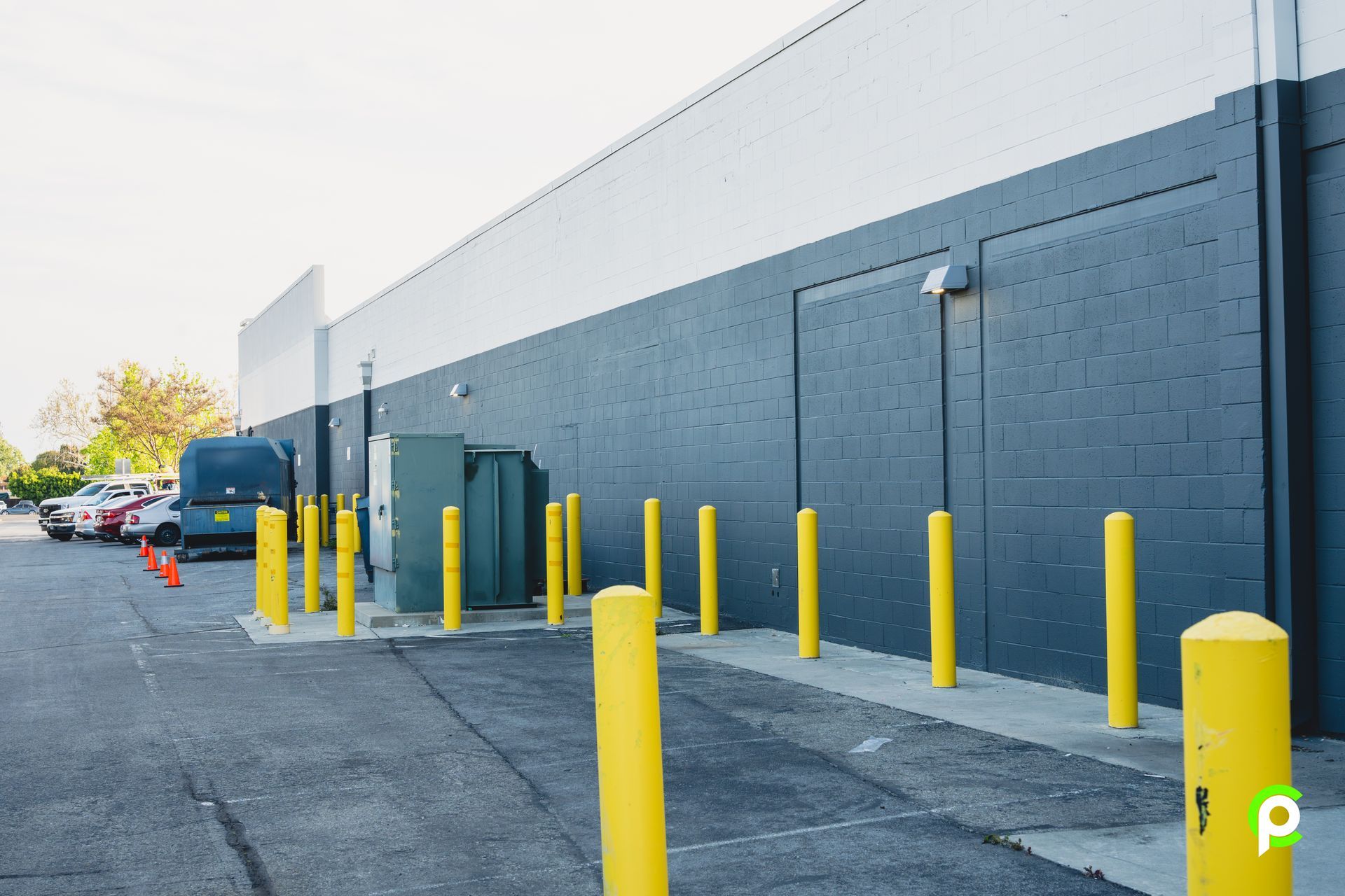 A parking lot with yellow poles in front of a building.