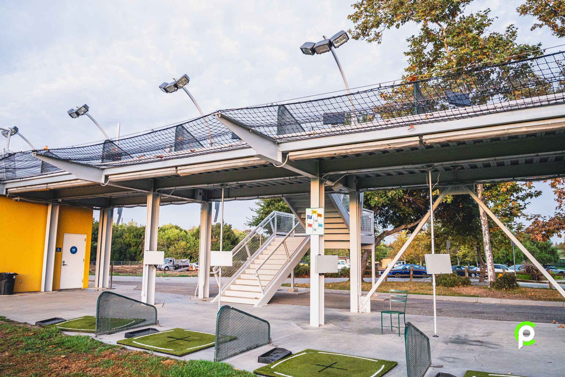A golf course with a yellow building in the background and stairs leading up to it.