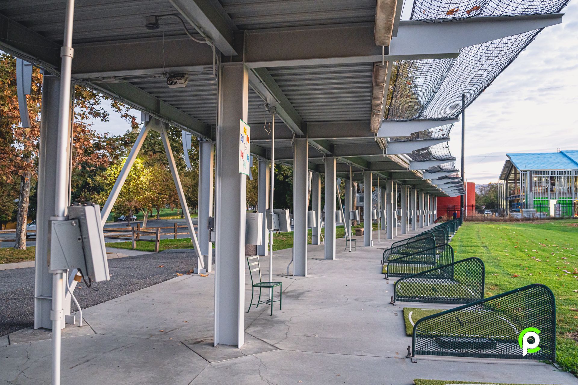 A row of benches under a covered walkway in a park.