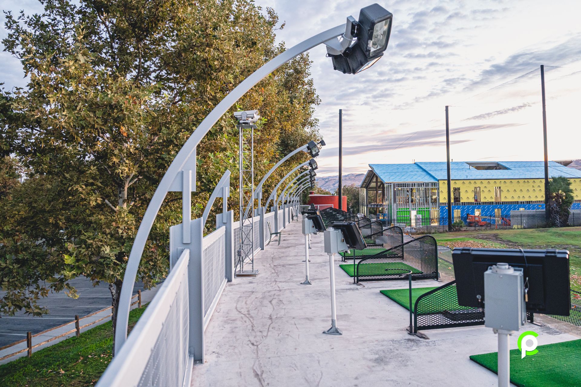 A row of golf simulators are lined up next to a fence.