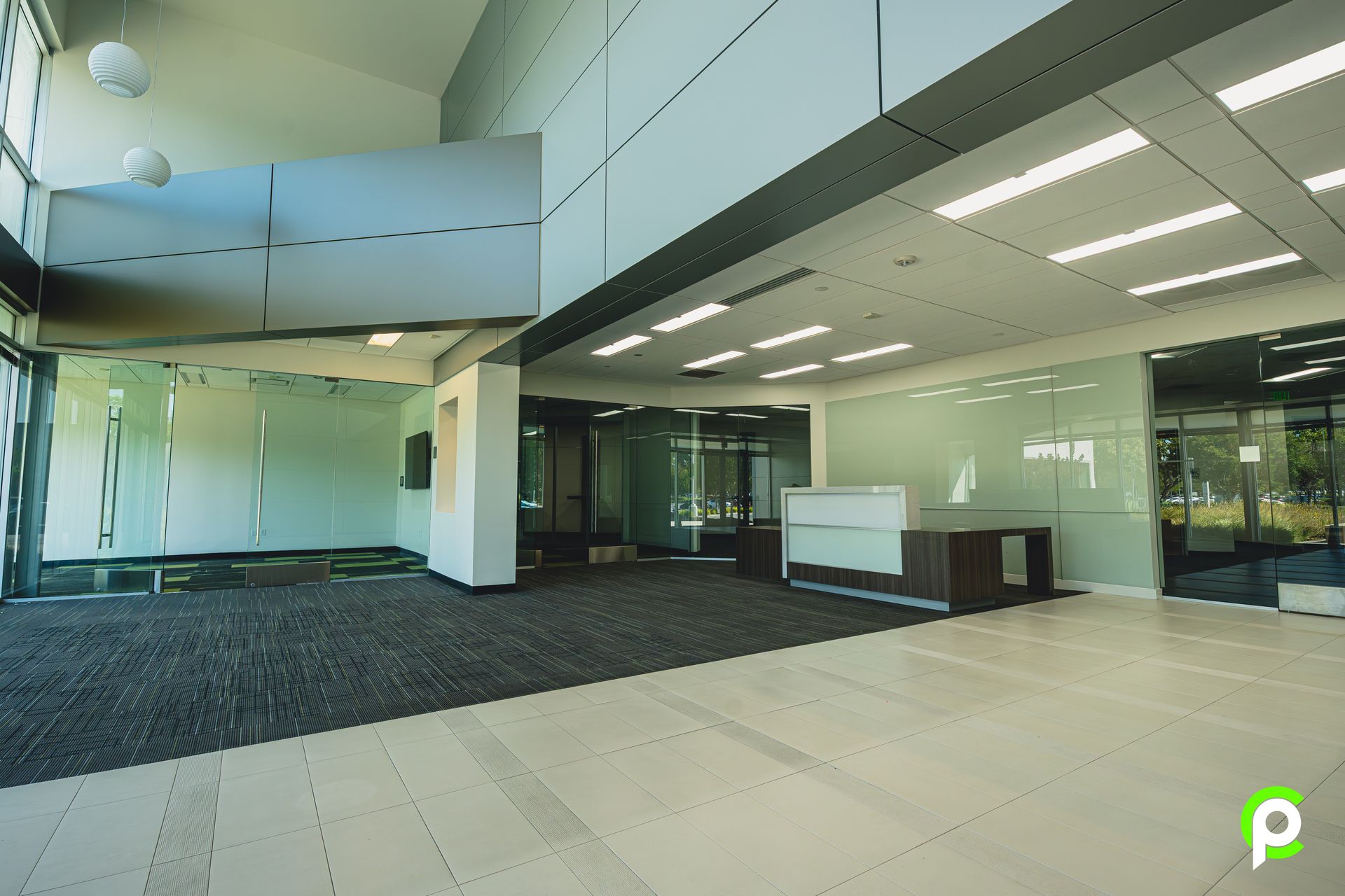 A large empty lobby with a reception desk in the middle of it.