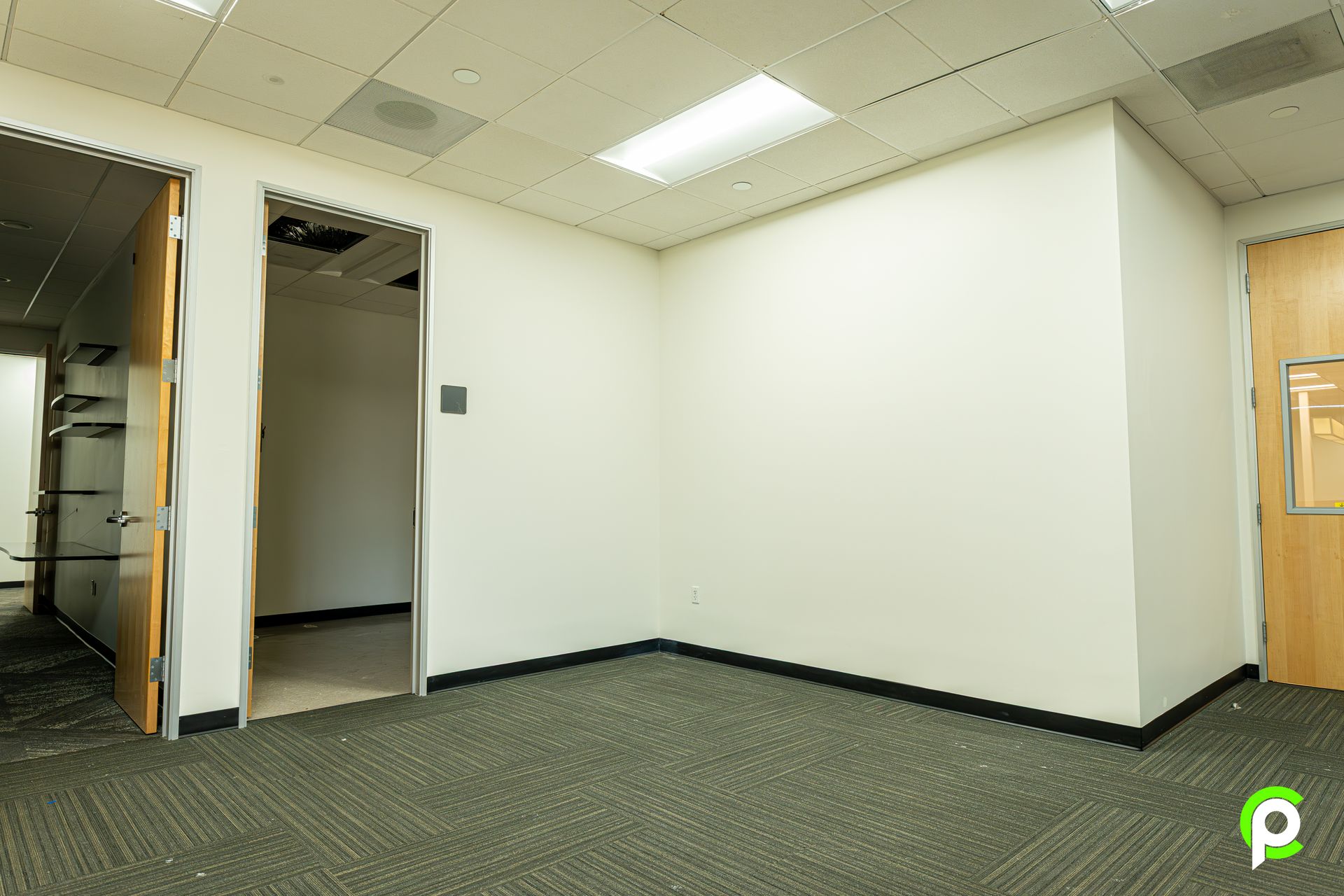 An empty room with a carpeted floor and white walls.