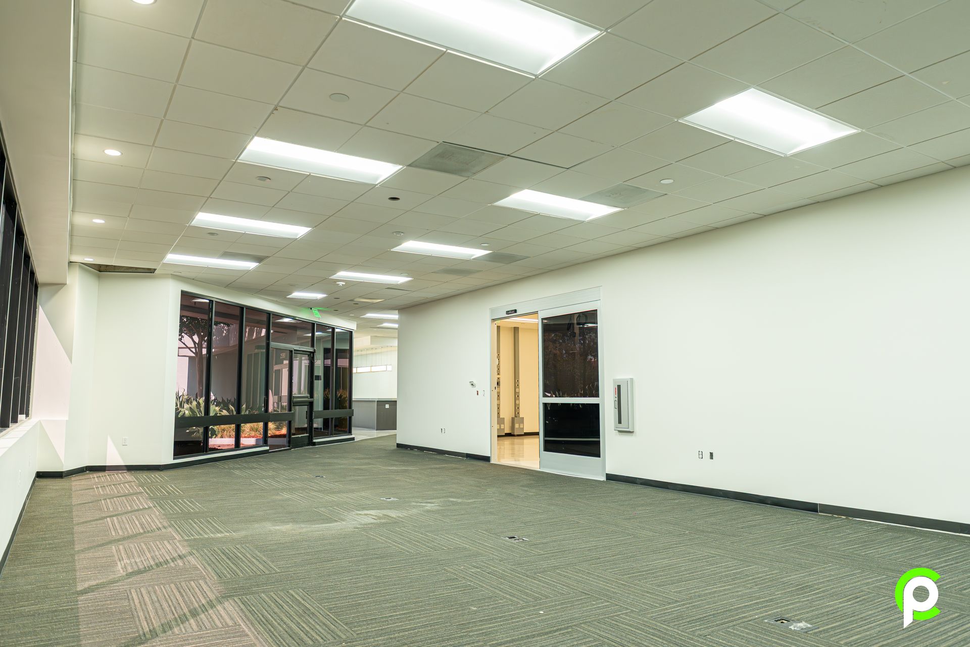 A large empty room with a lot of windows and lights on the ceiling.