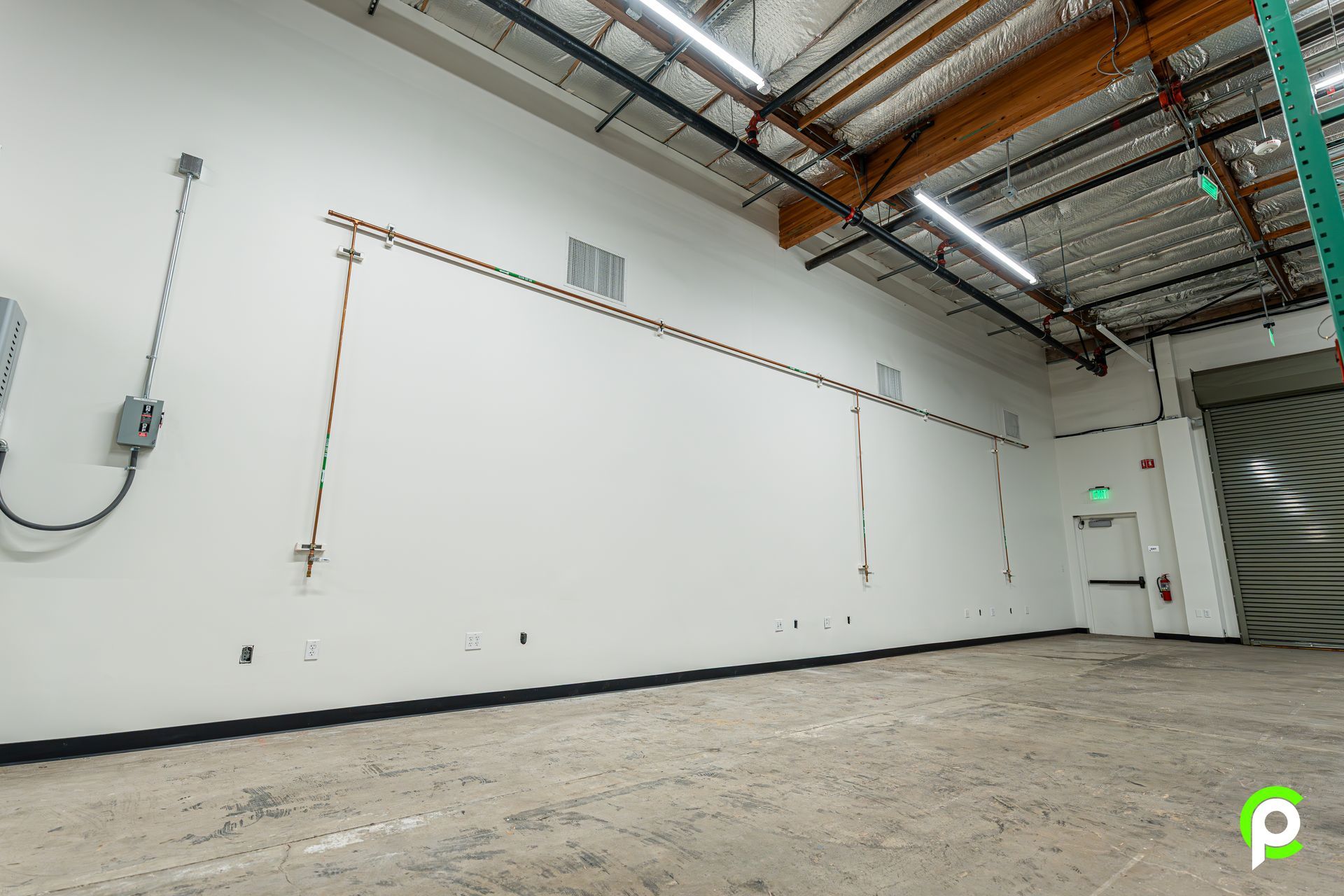 An empty warehouse with a large white wall and a door.