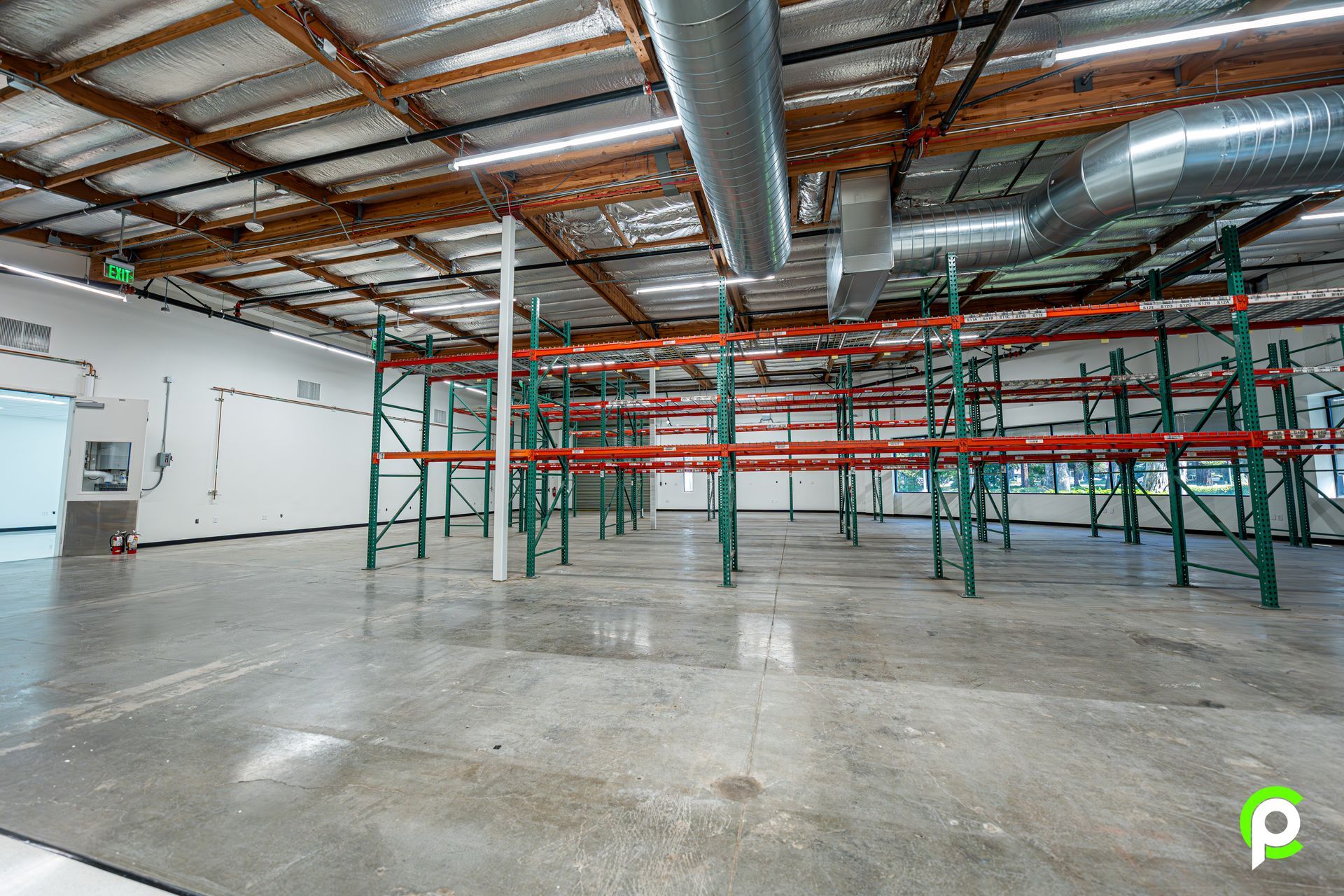 A large empty warehouse with lots of shelves and pipes.
