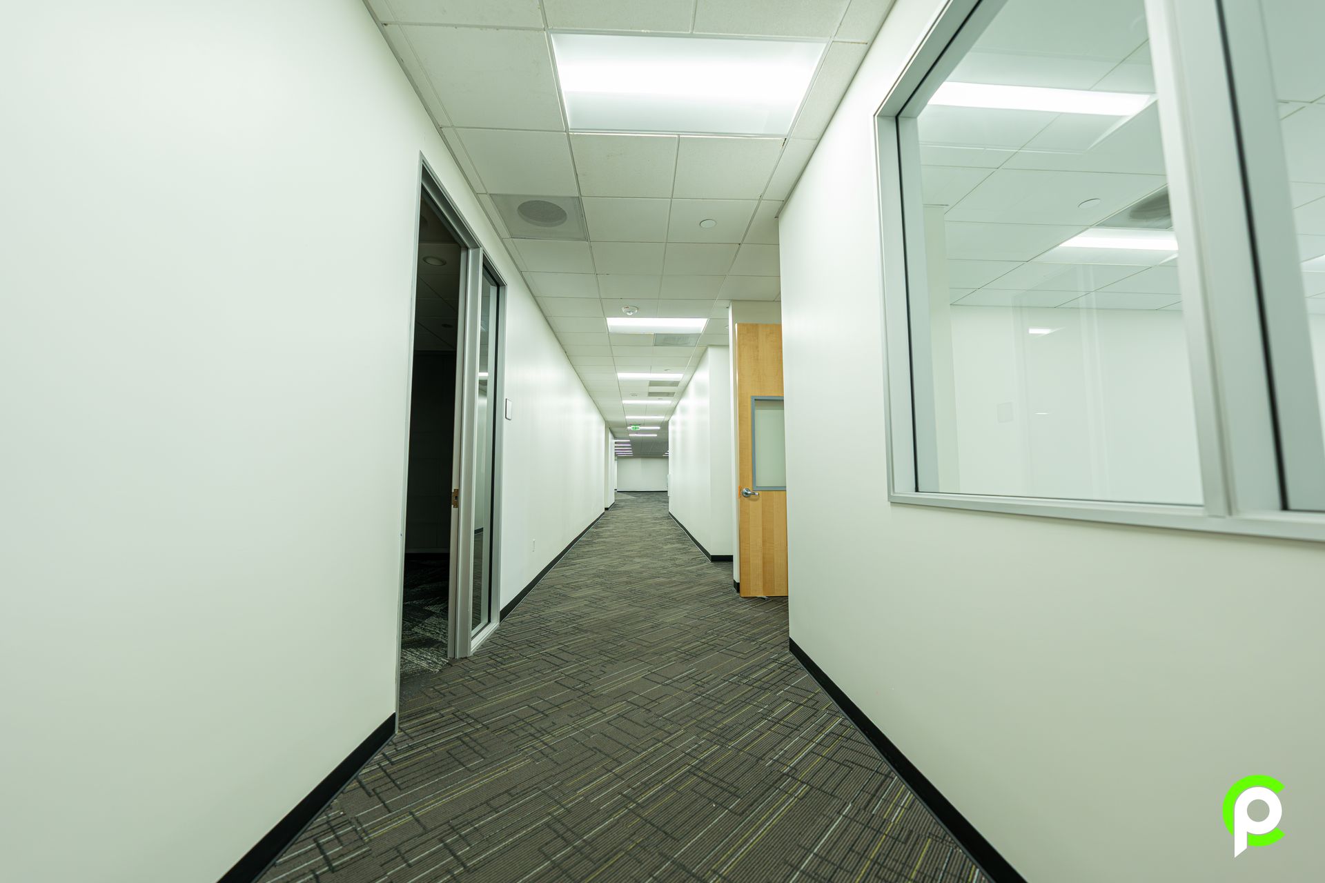 A long hallway with white walls and a window in an office building.