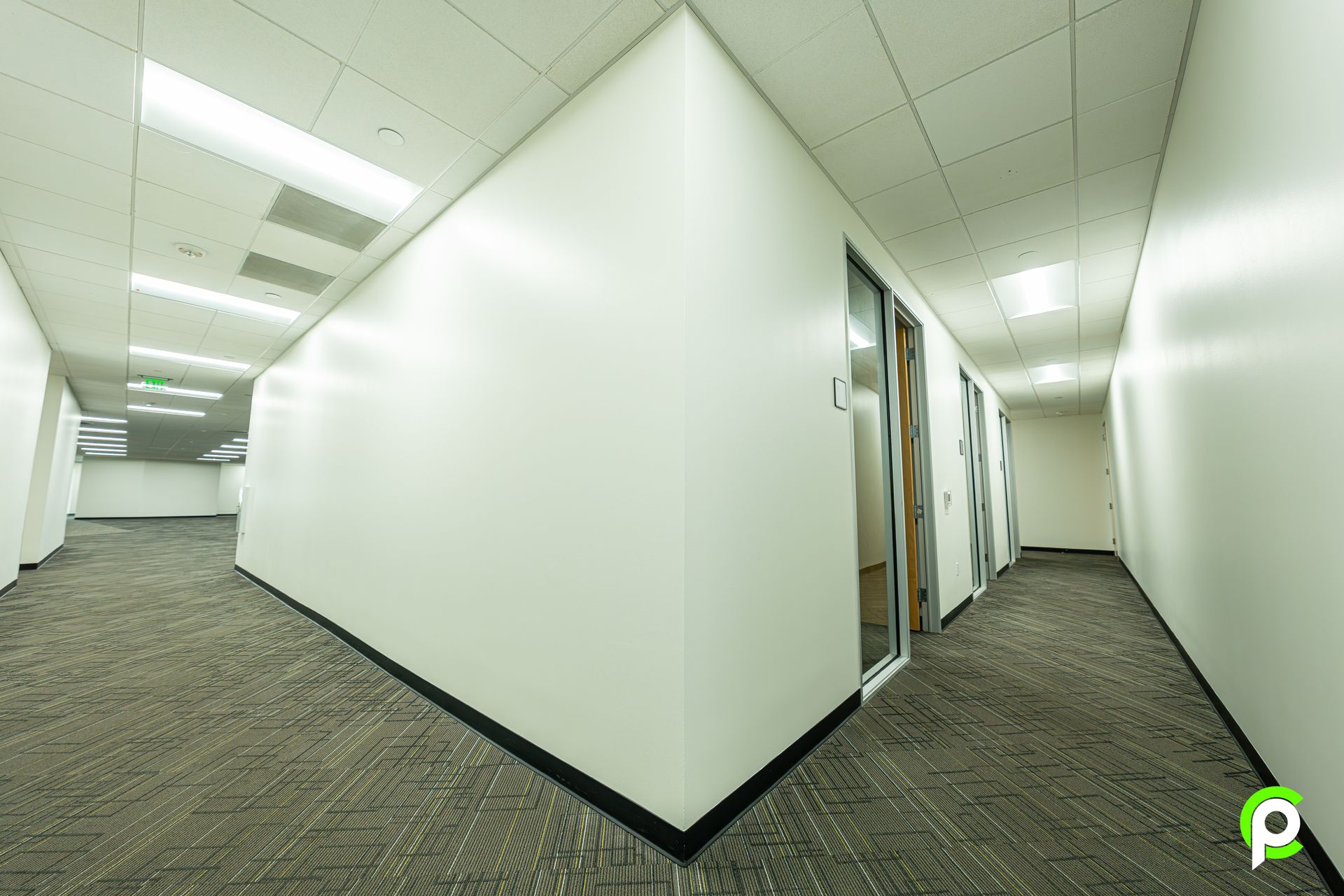 A long hallway with white walls and a carpeted floor in an office building.