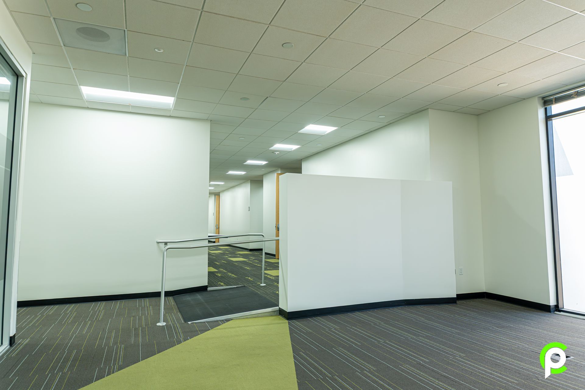 An empty office with a green carpet and white walls.