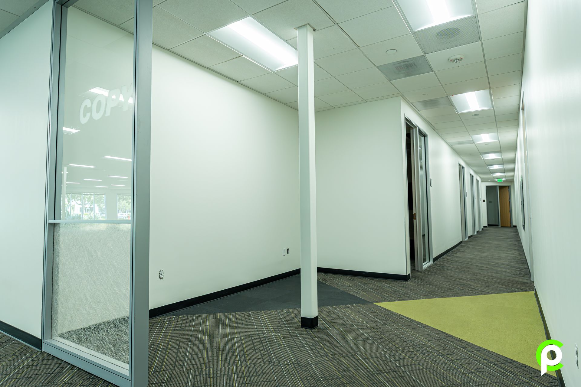 A long hallway with a glass door that says ' copy ' on it