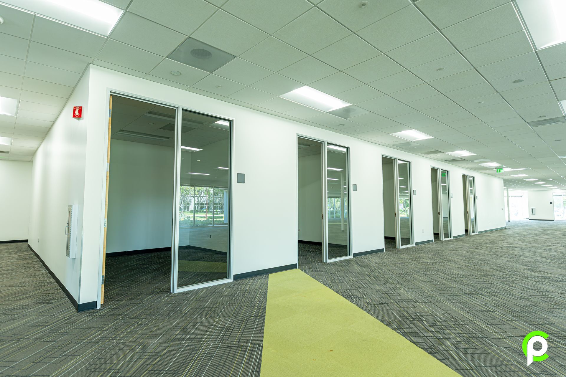 A large empty office building with a green carpet and white walls.