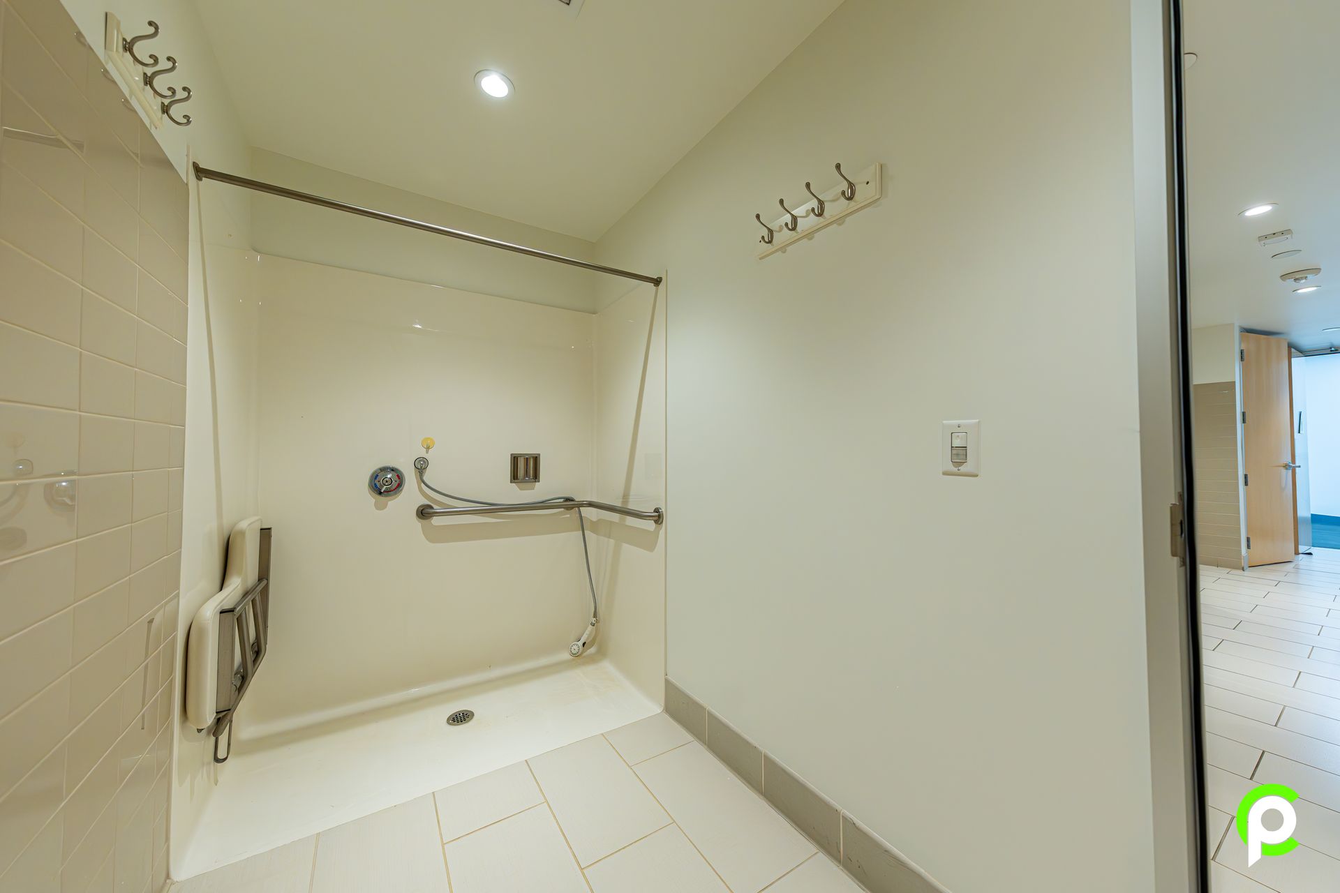 A bathroom with a walk in shower and a railing.