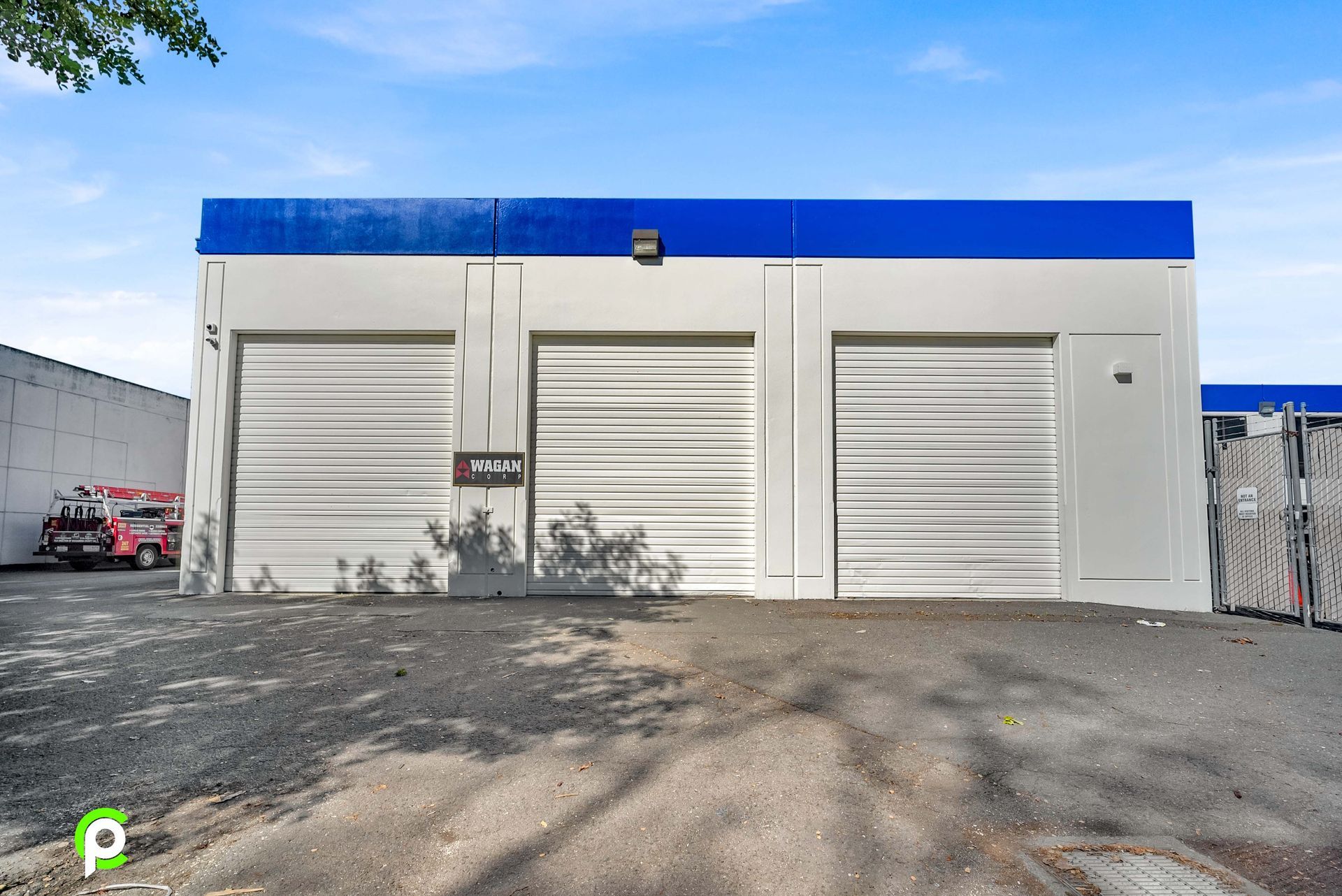A white building with a blue roof and white garage doors.