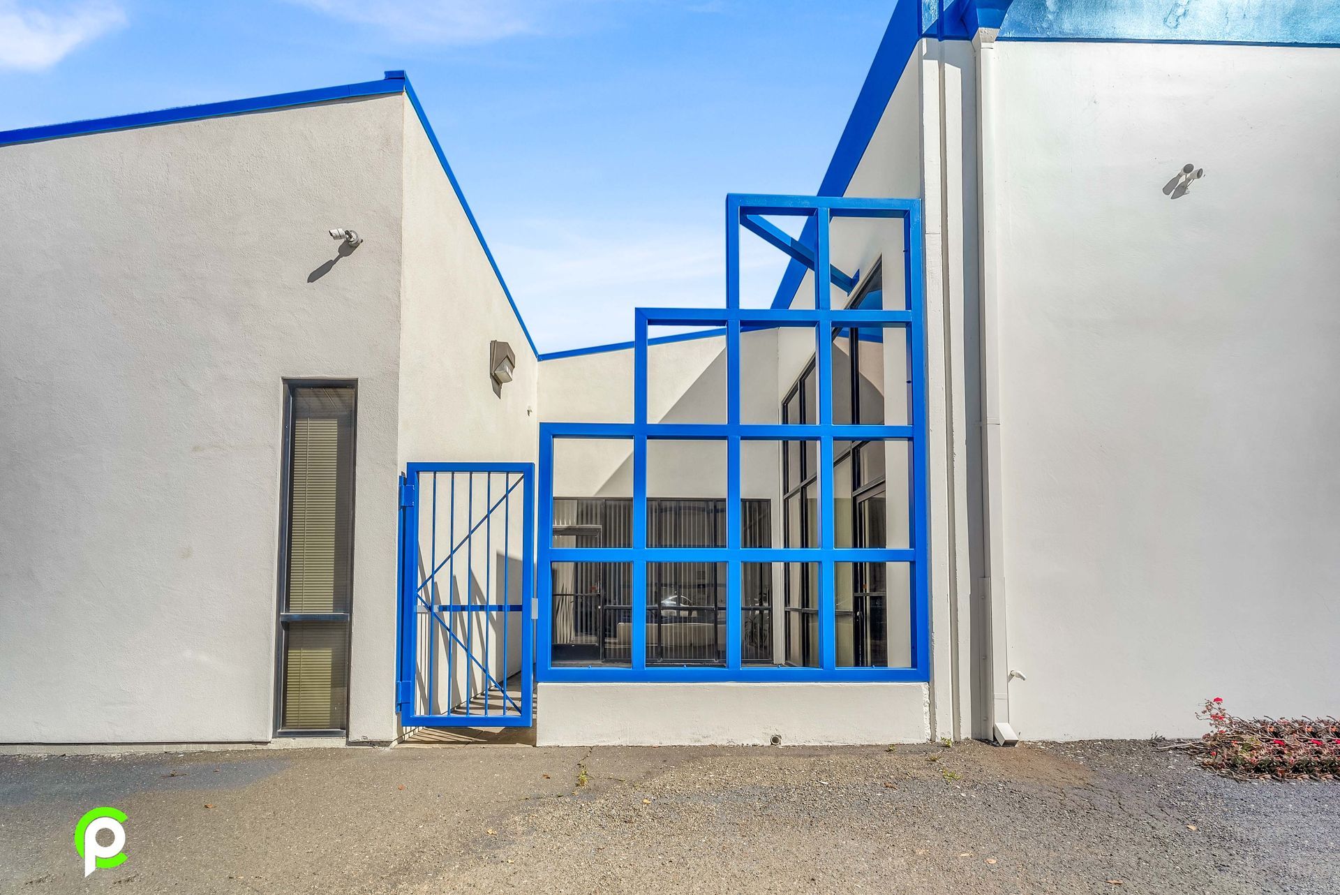 A white building with blue windows and a blue gate
