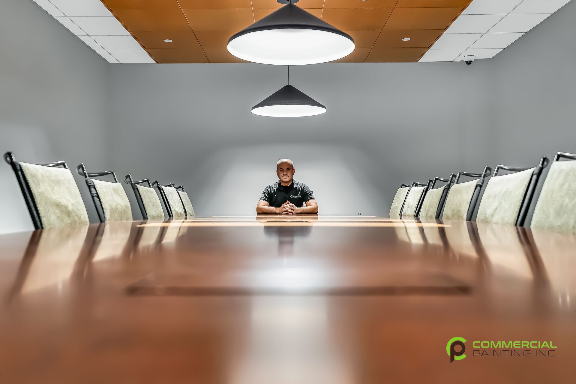 A man is sitting at a long conference table in a conference room.