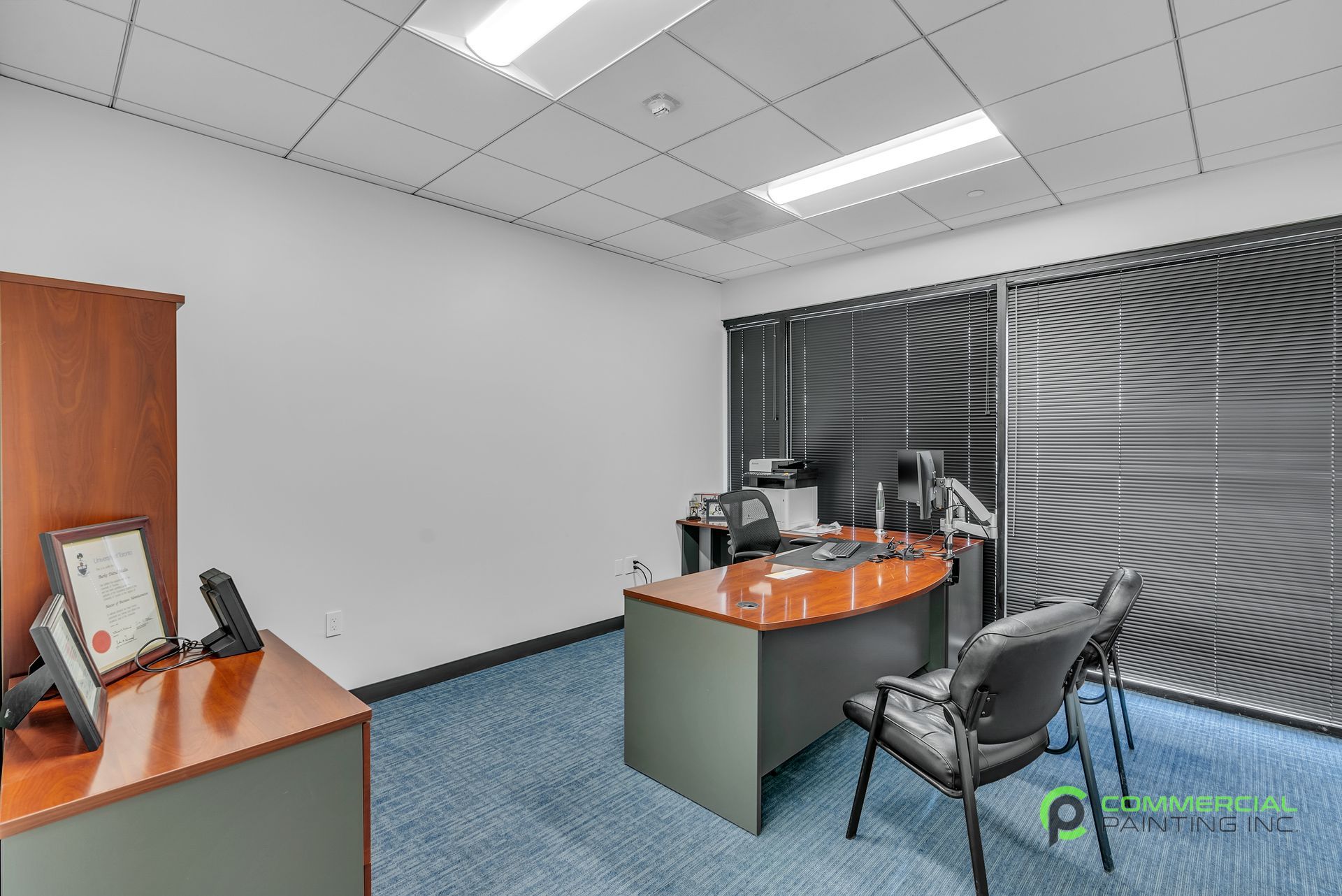 A small office with a desk , chairs and blinds.