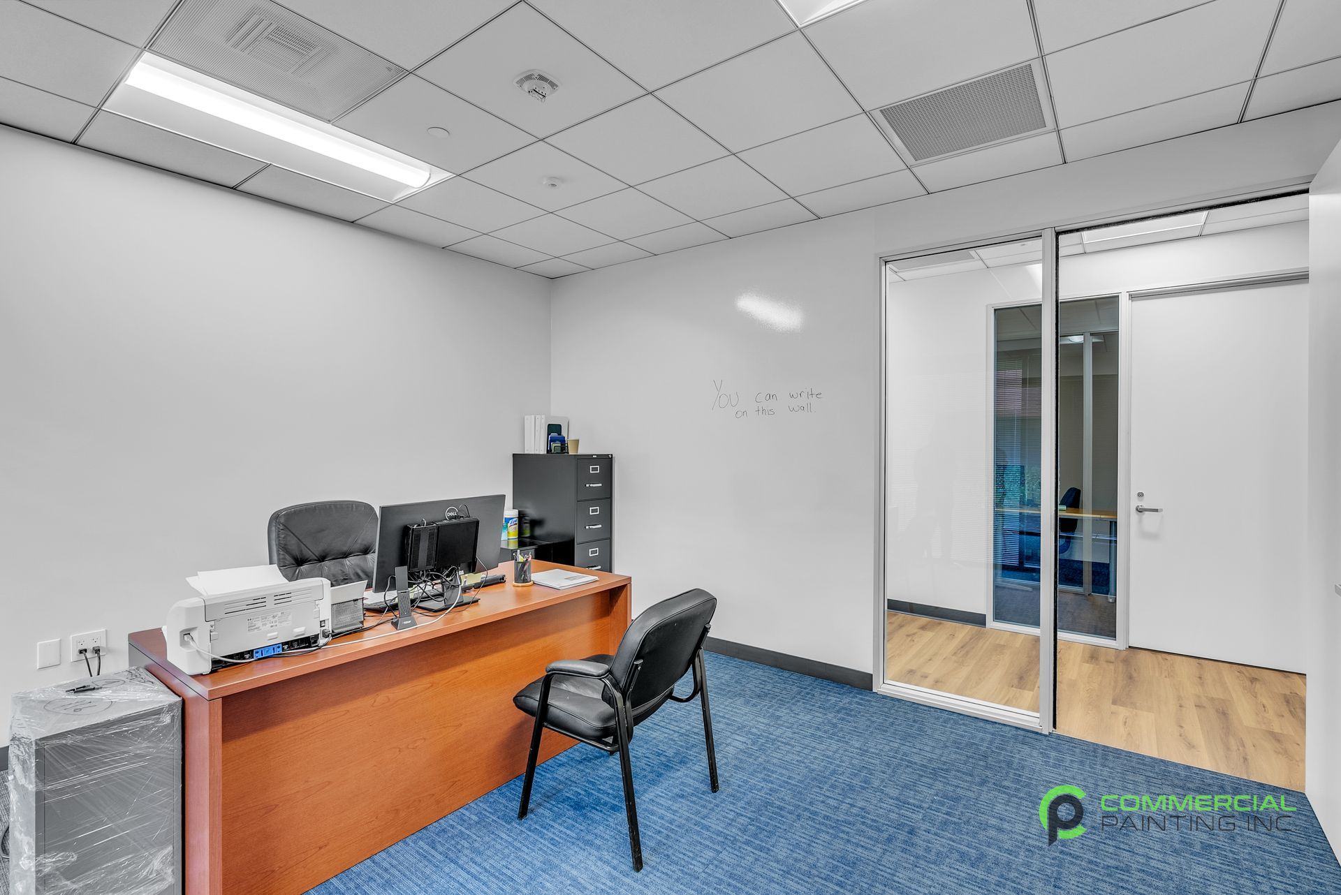 A small office with a desk , chair , computer and printer.