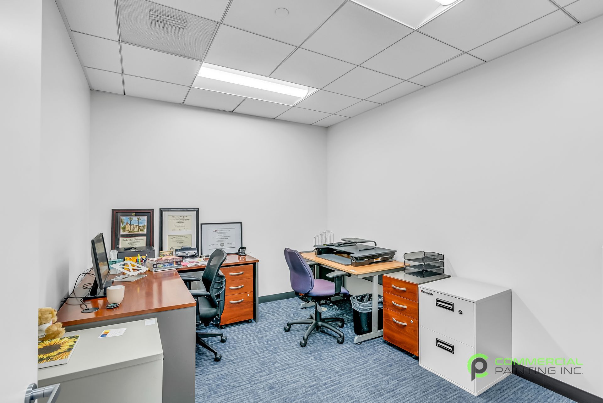 A small office with two desks and two chairs.
