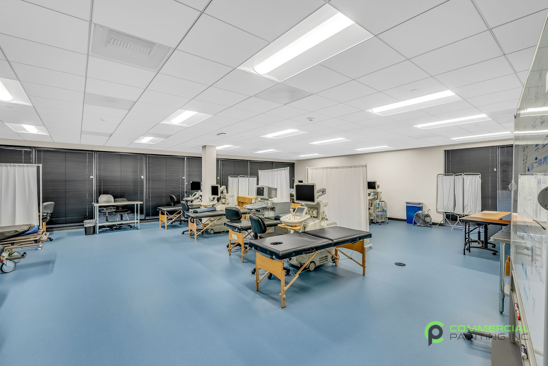 A large room with blue floors and tables in a hospital.