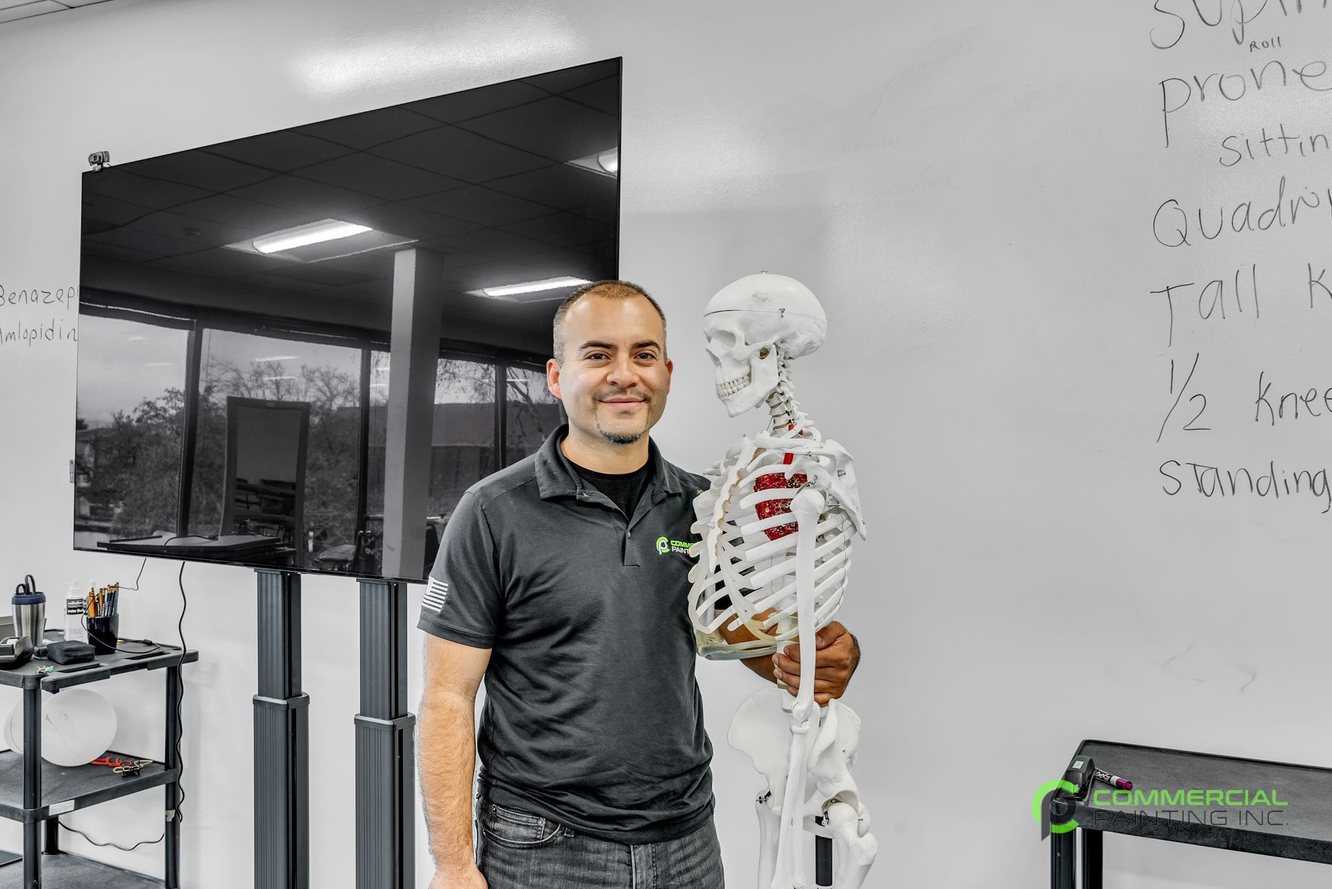 A man is standing next to a skeleton in a gym.