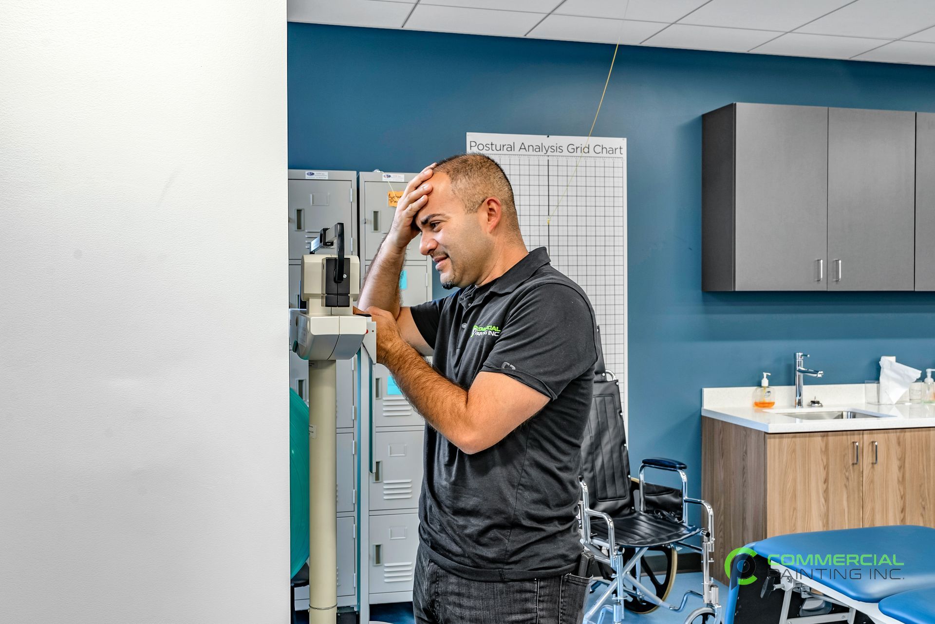 A man is standing in a room with his hand on his head.