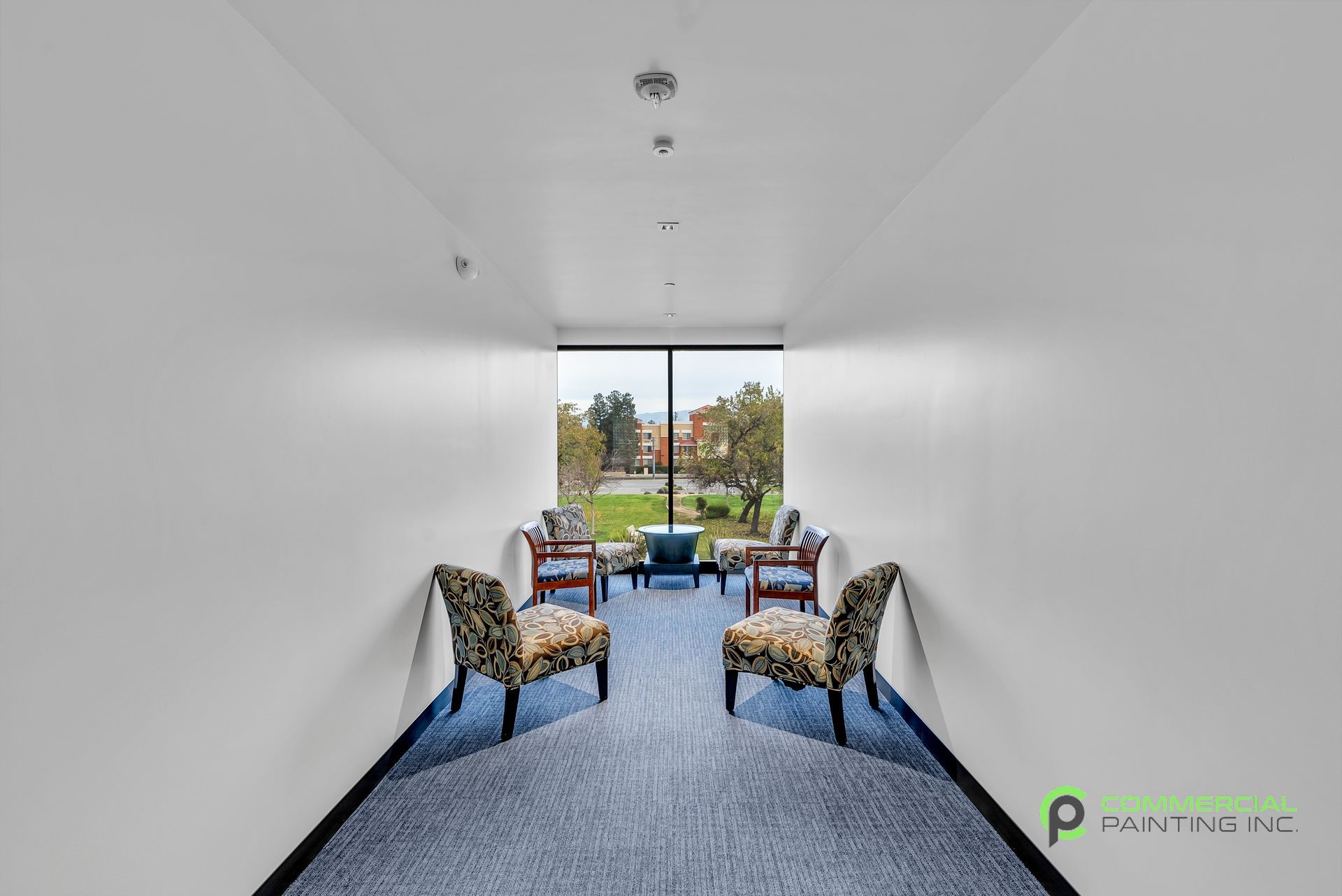 A long hallway with chairs and a large window.