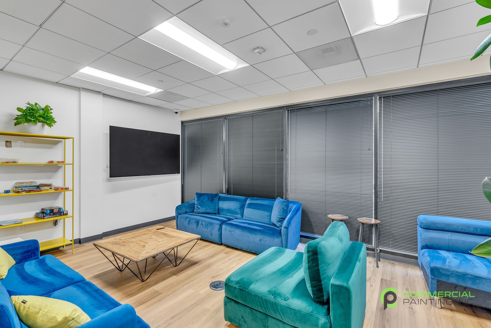 A living room with blue couches , chairs , a coffee table and a flat screen tv.