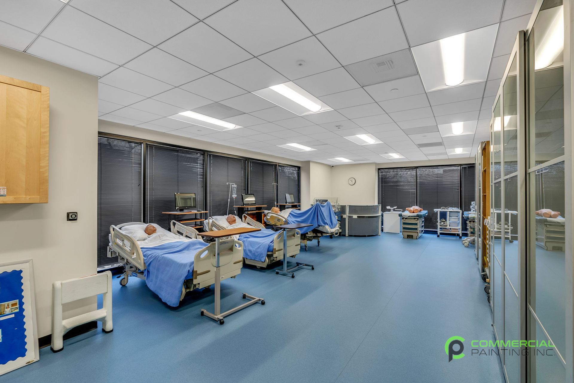 A hospital room with a lot of beds and a blue floor.