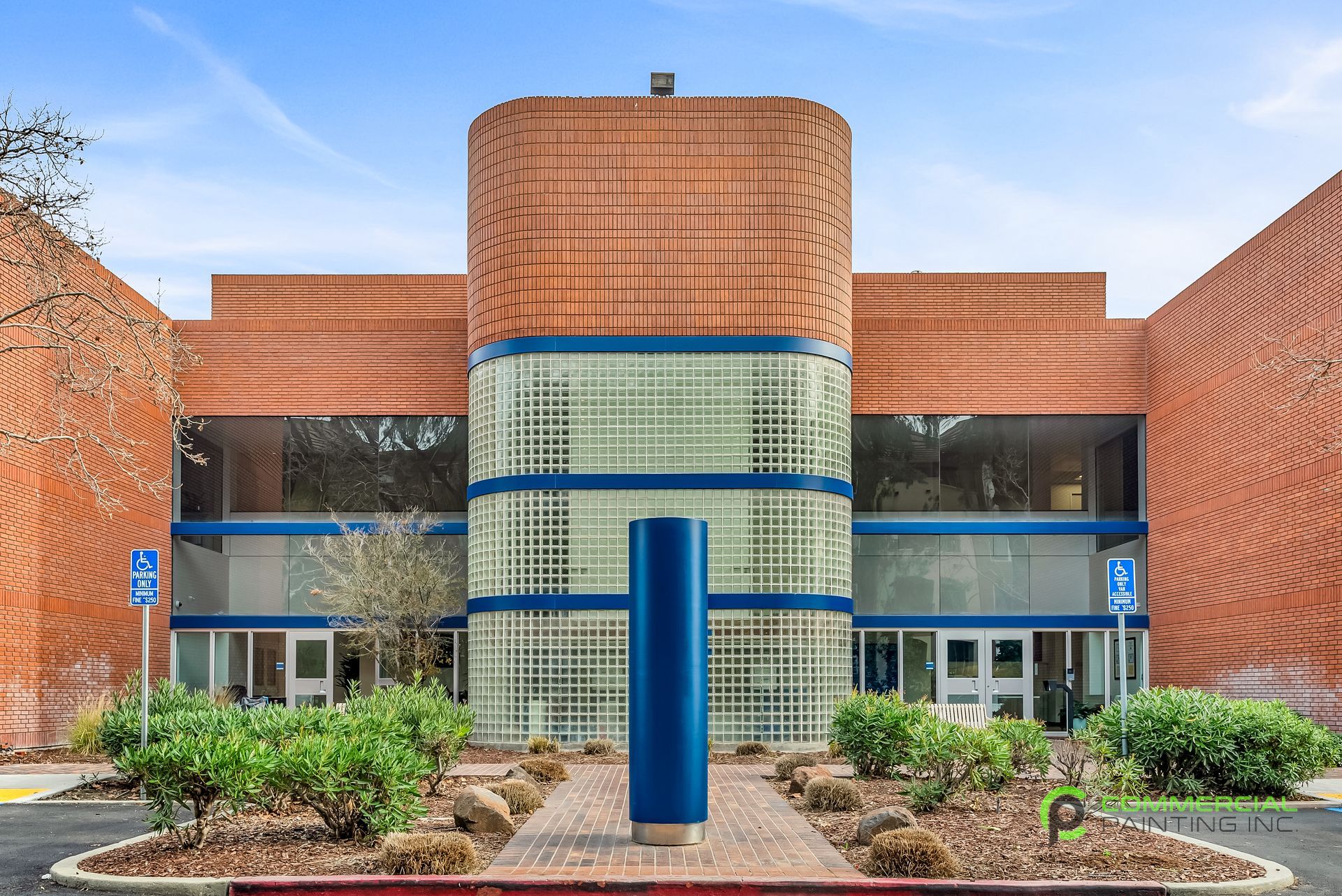 A large brick building with a blue pillar in front of it.