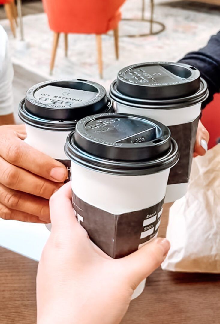 A group of people are toasting with three cups of coffee.