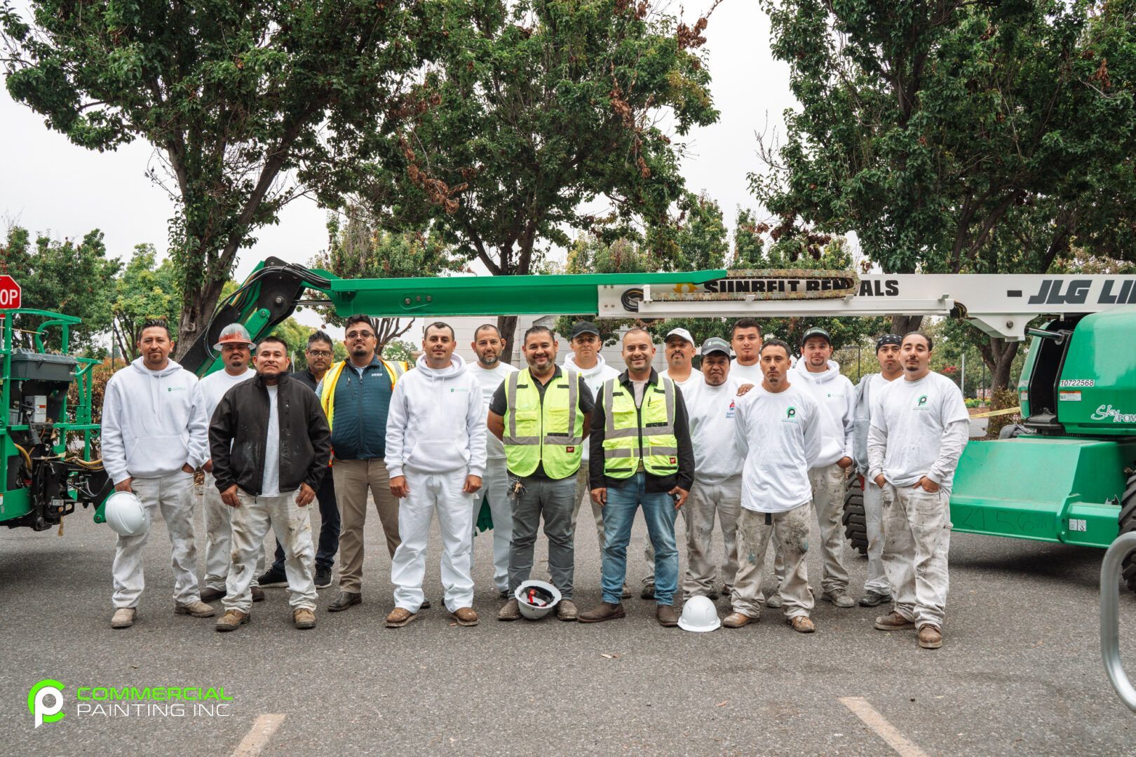 A group of construction workers are posing for a picture in front of a crane.