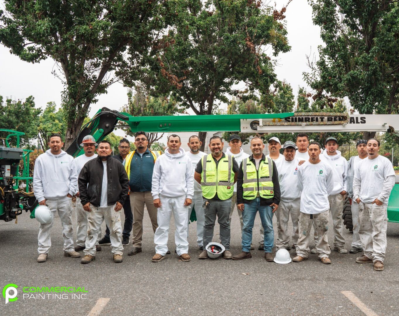 A group of construction workers are posing for a picture in front of a crane.