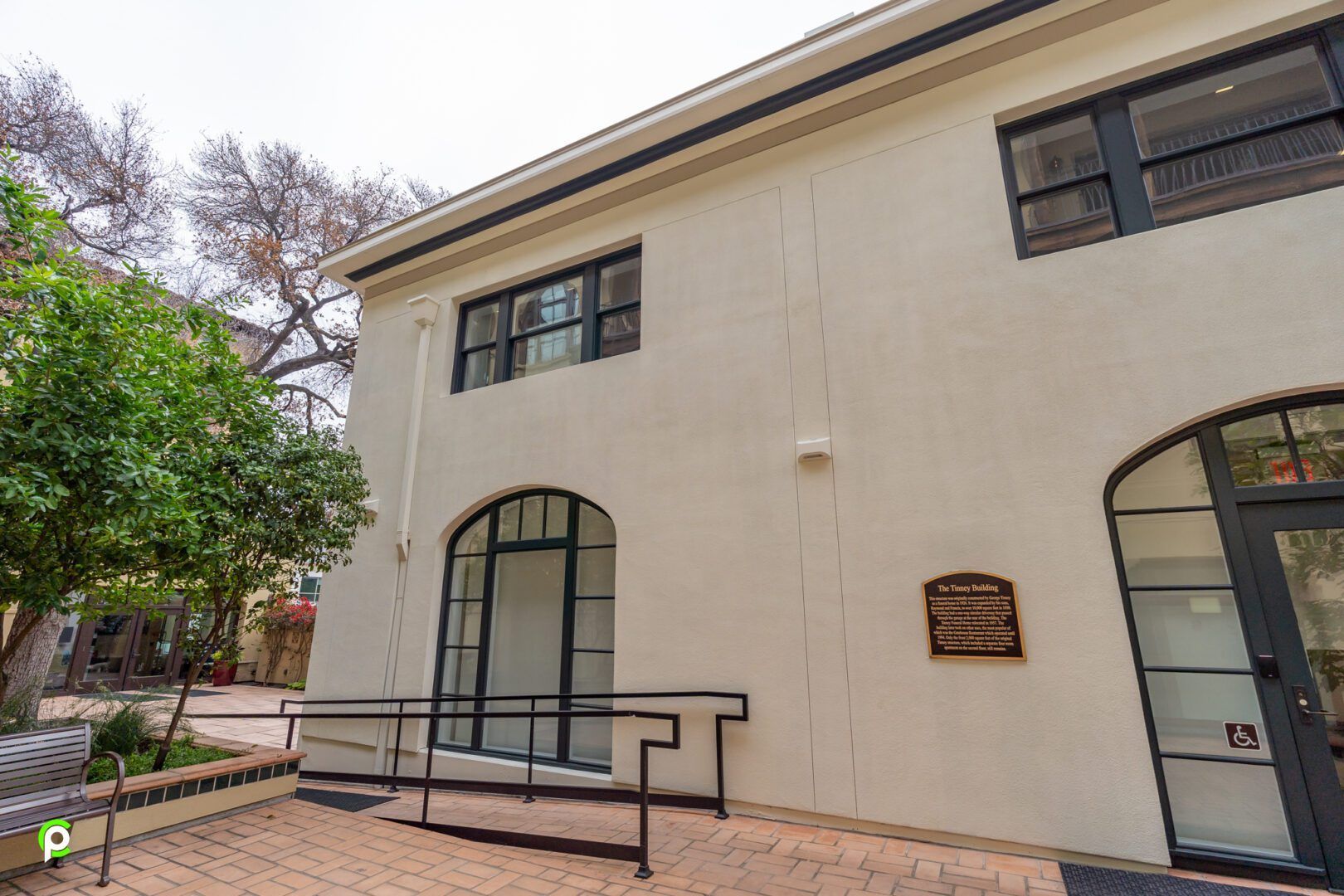 A large white building with a ramp and a bench in front of it.
