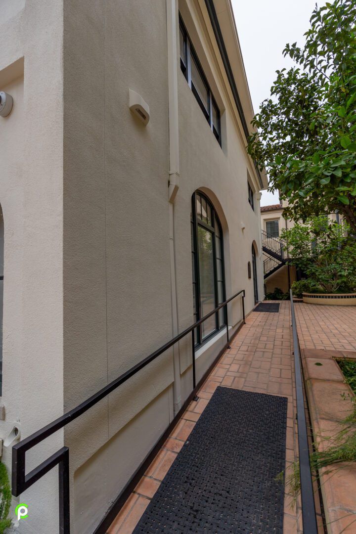 A white building with a black mat on the sidewalk