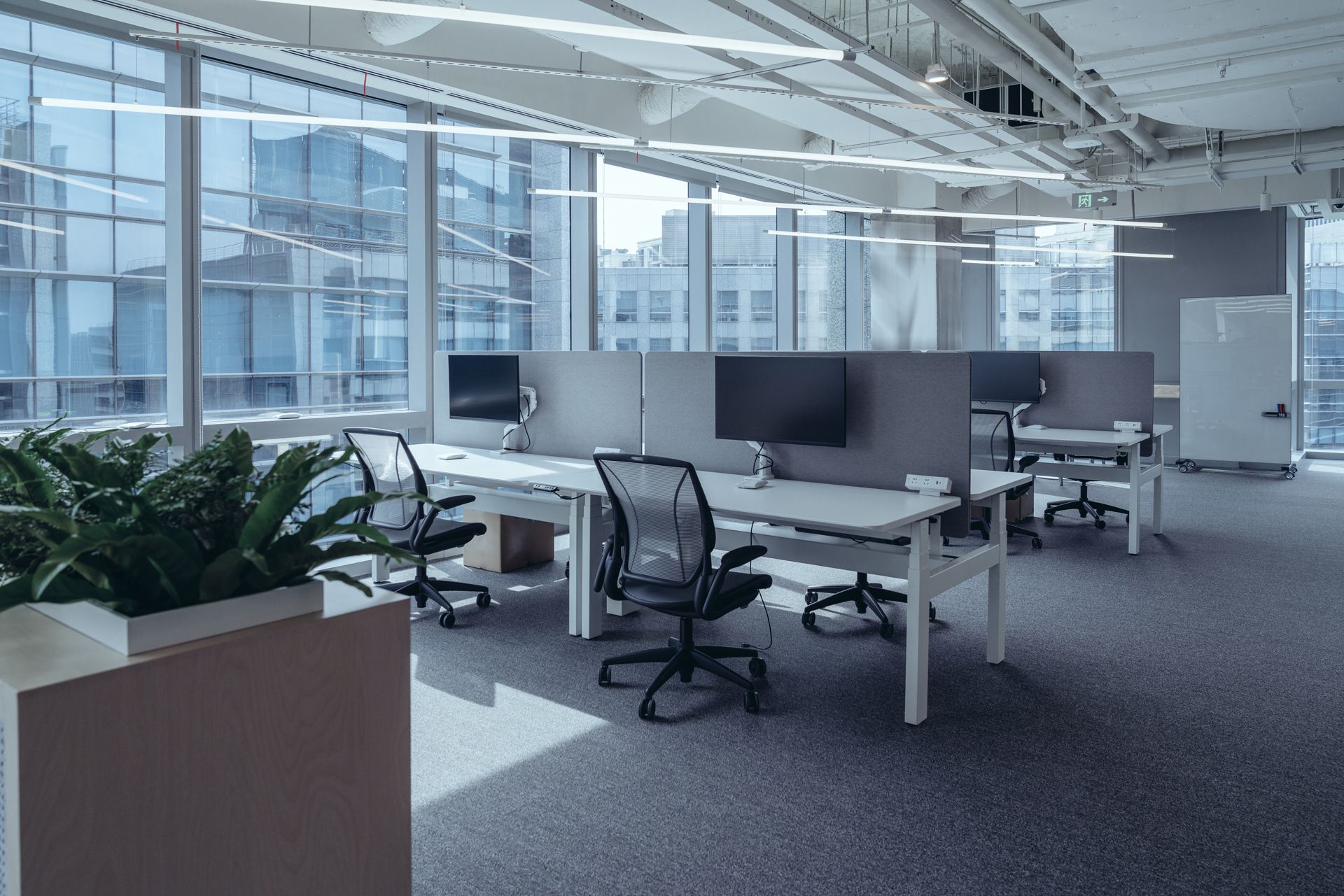 A large empty office with a lot of windows and desks and chairs.