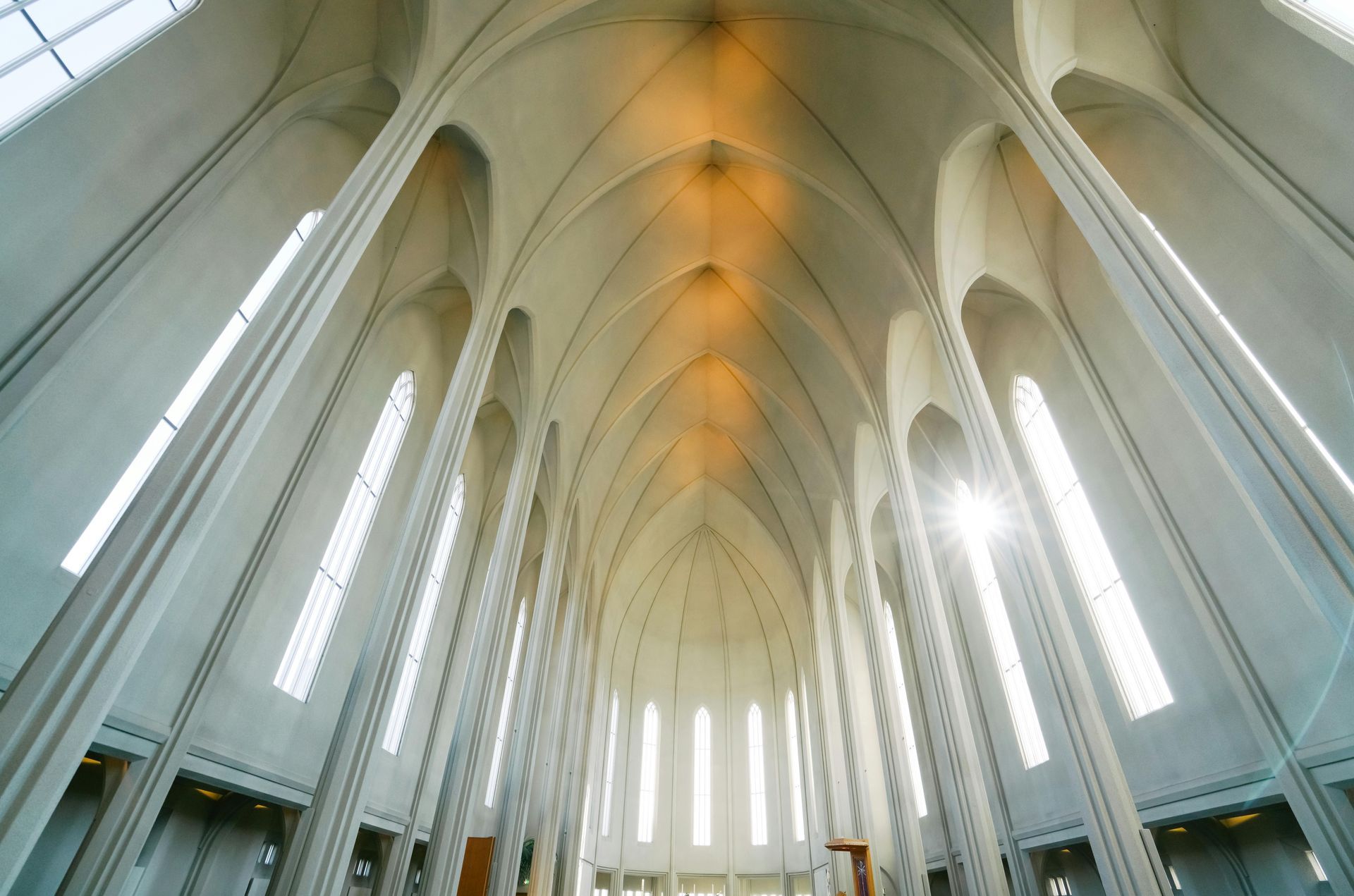 Interior view of Hallgrímskirkja church in Iceland. High vaulted ceiling, sunlight streaming through tall windows.