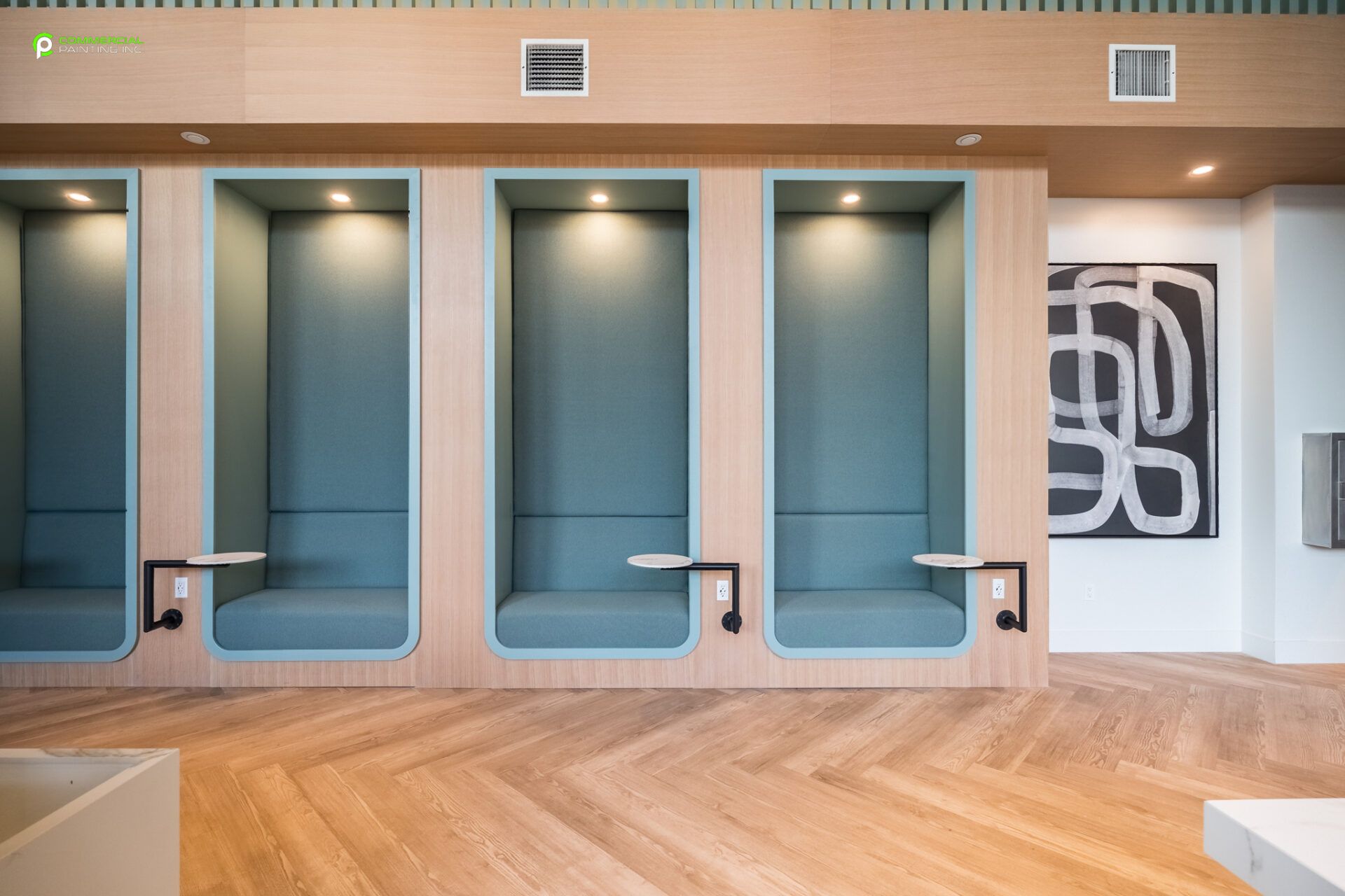A row of booths with tables in a room with a wooden floor.