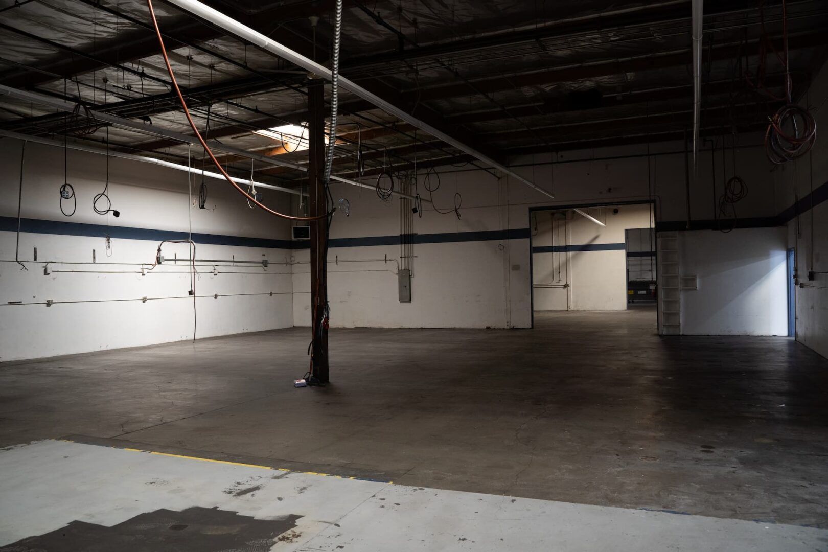 An empty warehouse with white walls and a concrete floor