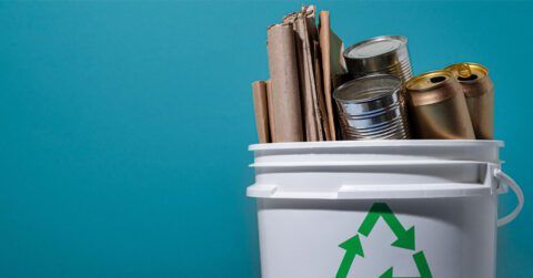 A recycling bin filled with cans , paper , and metal.