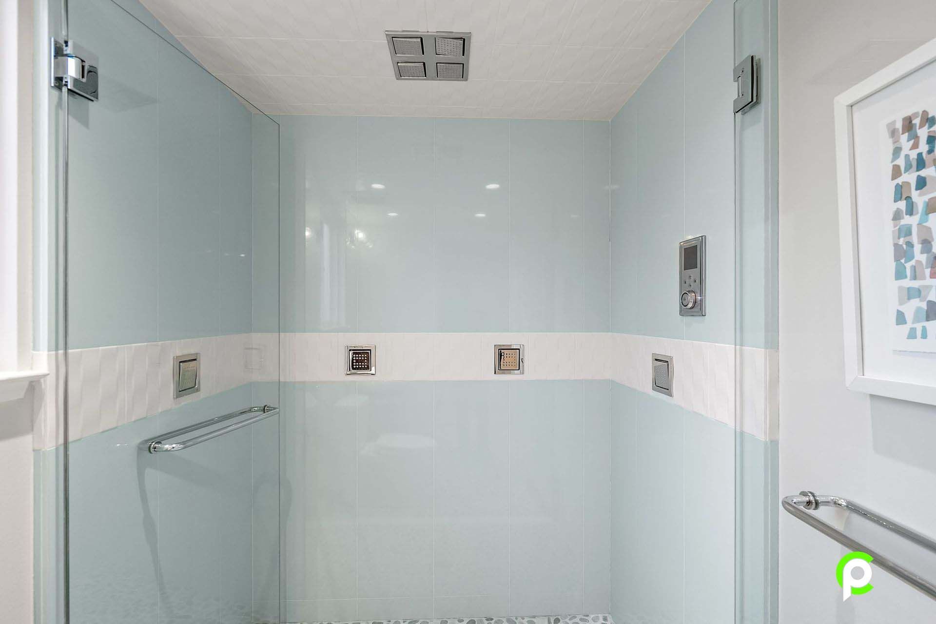 A bathroom with a walk in shower and a glass door.
