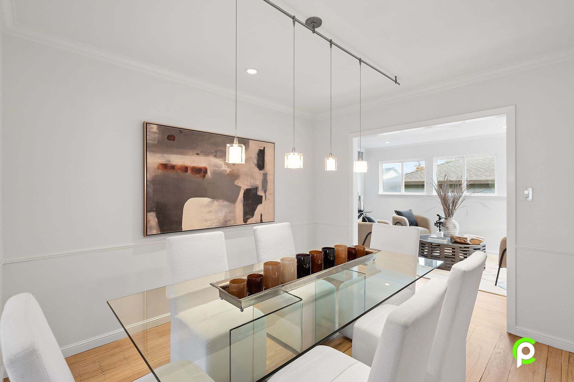 A dining room with a glass table and white chairs
