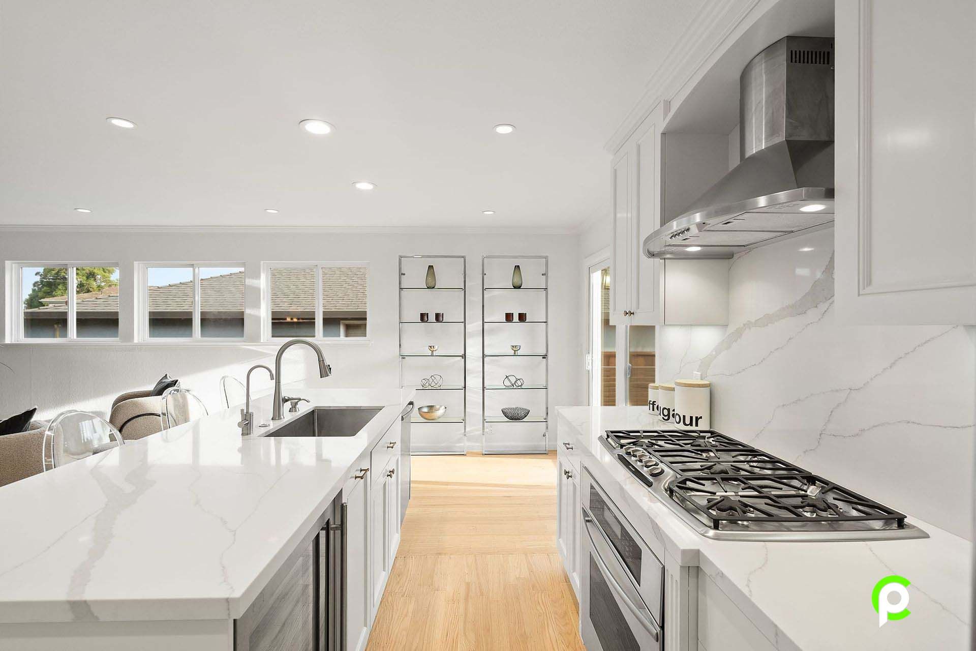 A kitchen with white cabinets , a stove top oven , a sink , and a hood.