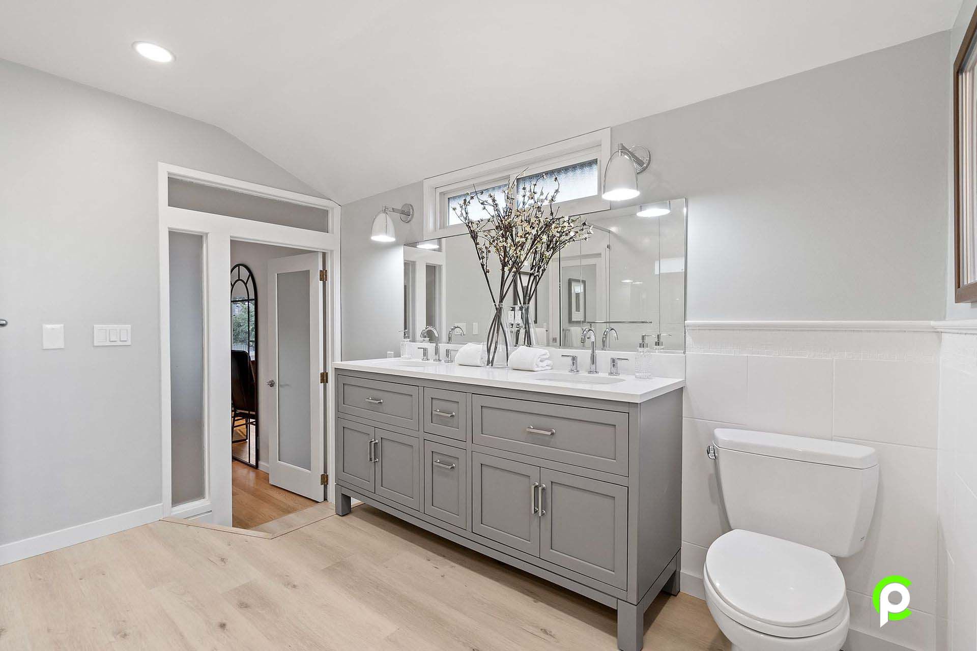 A bathroom with two sinks , a toilet and a window.