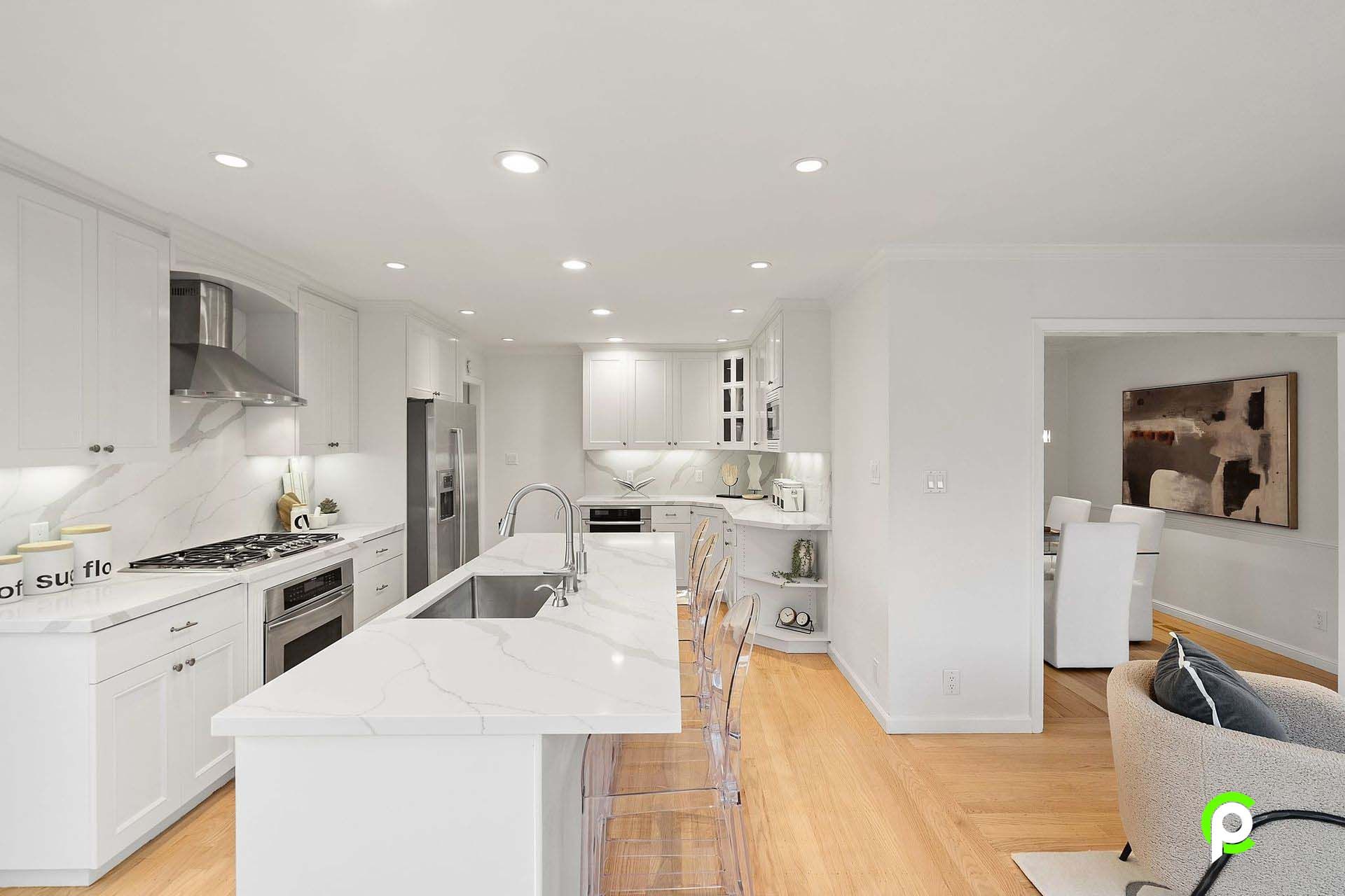 A kitchen with white cabinets and stainless steel appliances and a large island.