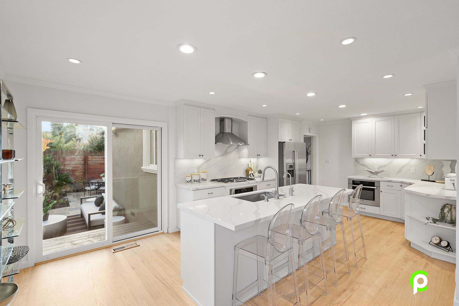 A kitchen with white cabinets and stainless steel appliances and a large island.